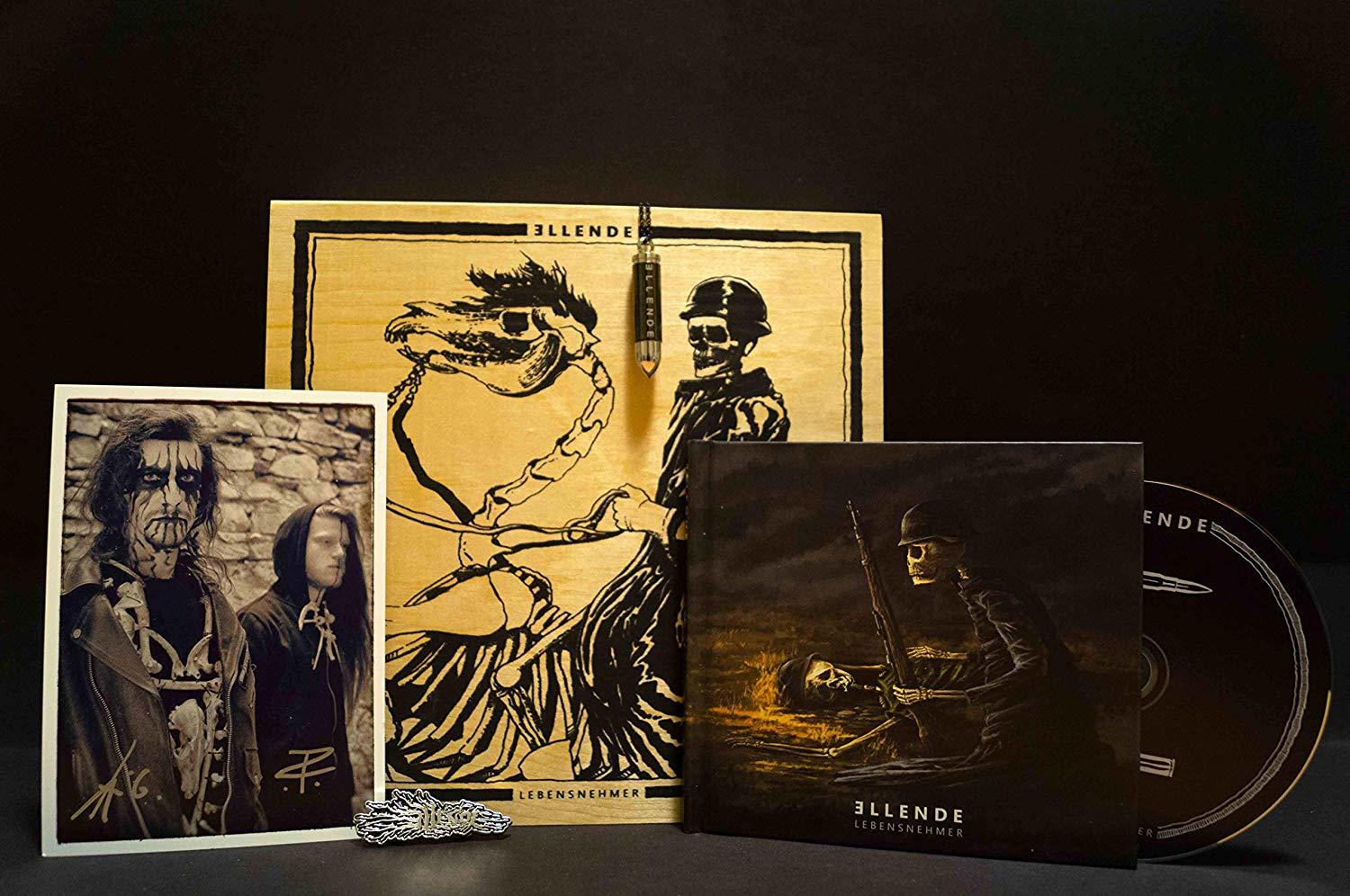 Eine Sammlung von Merchandise mit dunklem Thema: CD, Foto, Anstecknadel und Holzkiste.