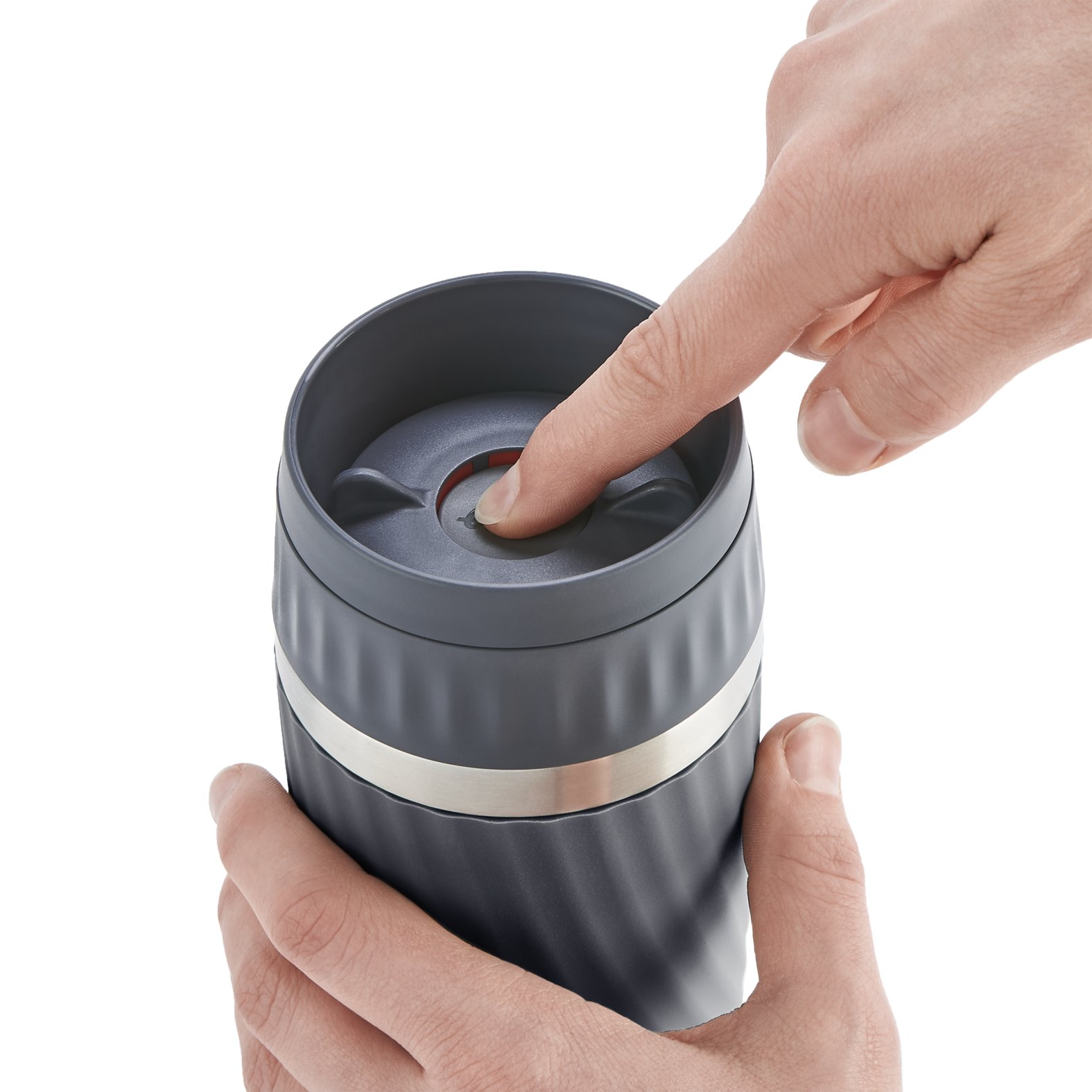 De vinger van een persoon drukt op een knop op een donkergrijze reismok met een zilveren band.
