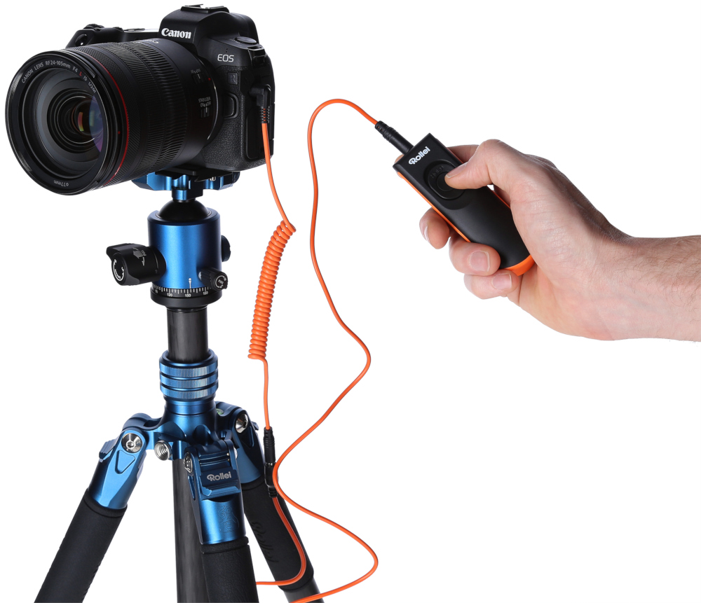 Appareil photo sur trépied, connecté à une télécommande tenue par une personne.