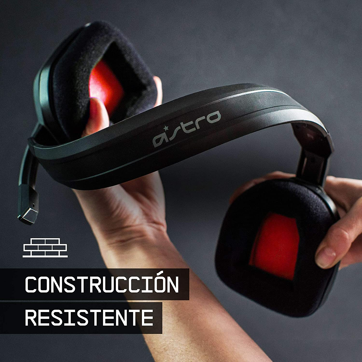 Un auricular negro sostenido por dos manos. El texto dice 'CONSTRUCCIÓN RESISTENTE'.
