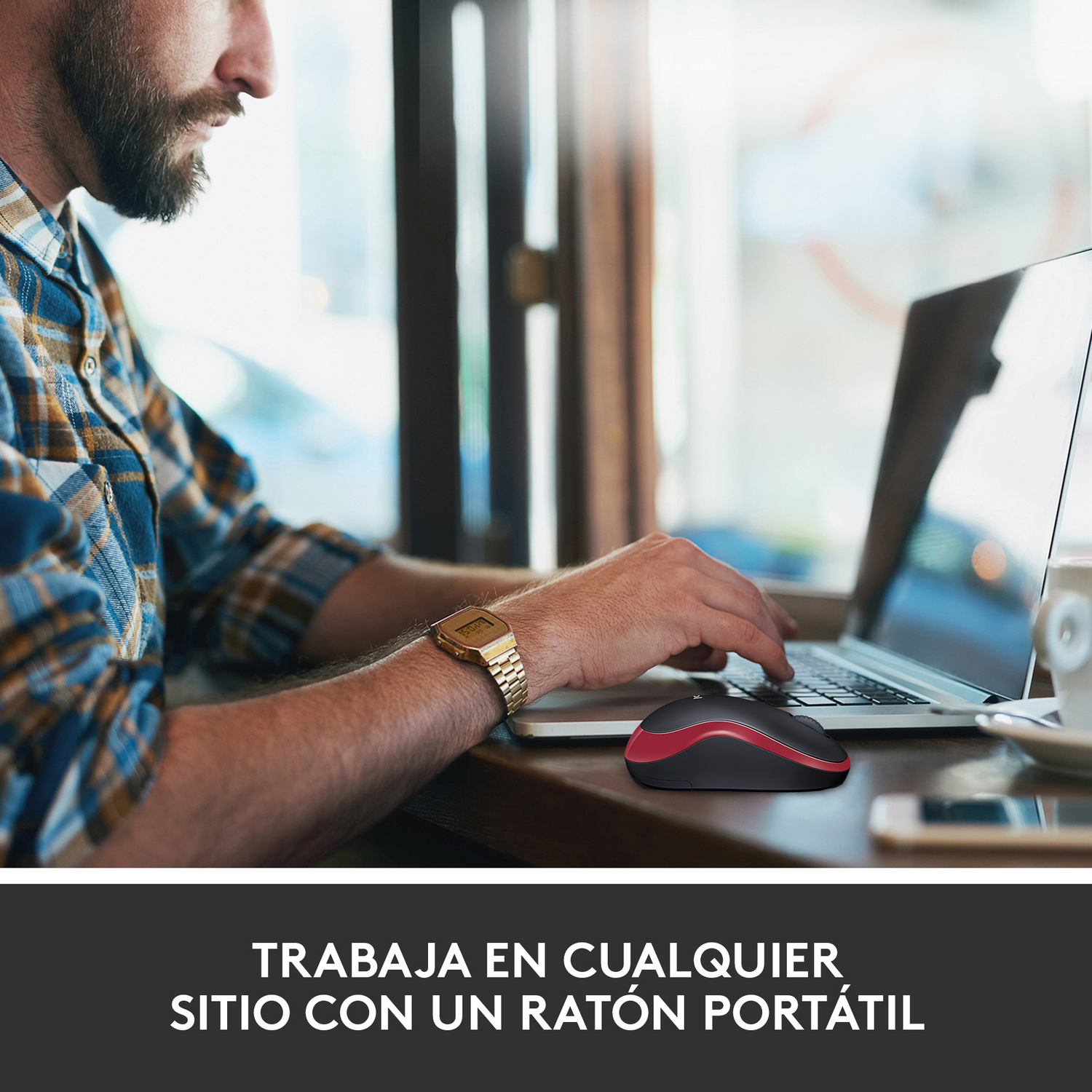 Un hombre usando una laptop con un ratón rojo y negro. Escena en un café.