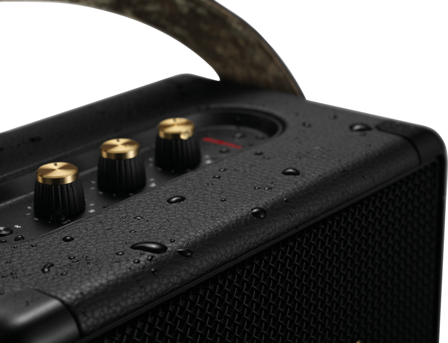 Close up of a black audio speaker with gold knobs, some water droplets, and a handle.