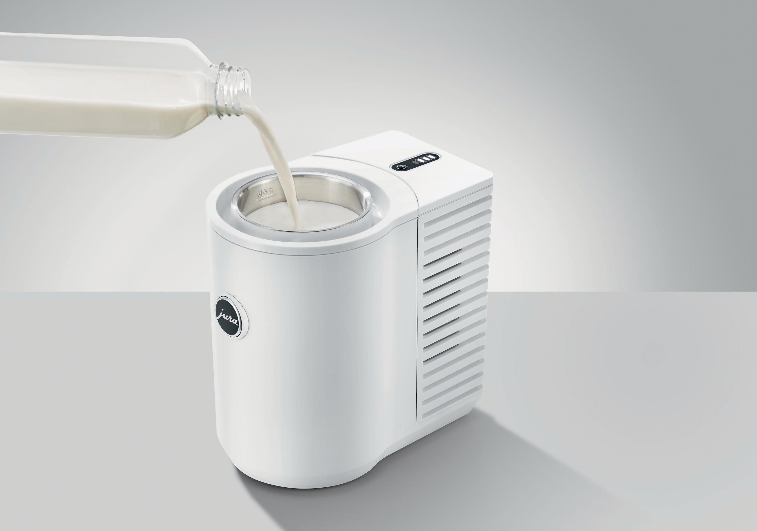 Weißer Milchaufschäumer, der mit Milch aus einer Flasche gefüllt wird. Jura-Logo ist sichtbar.
