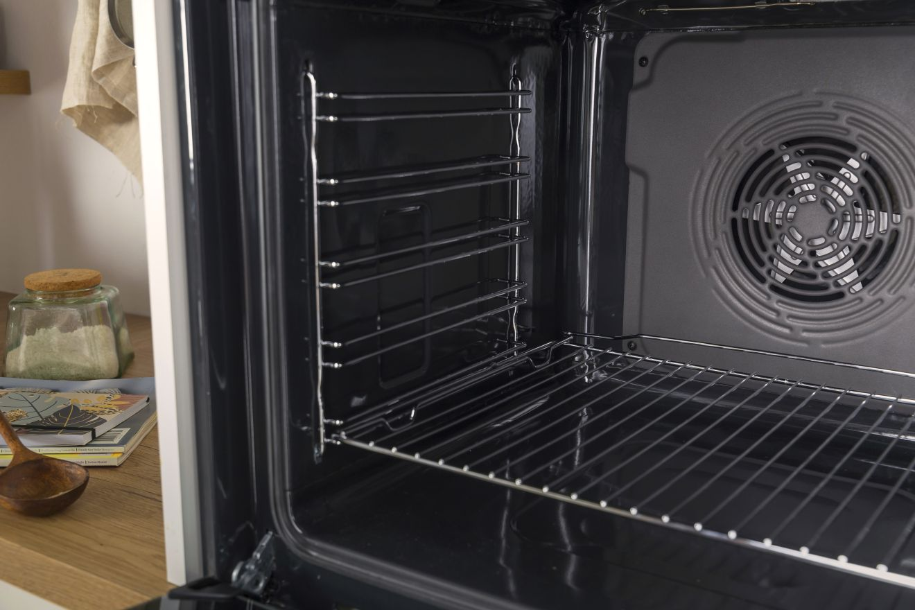 Egy sütő belseje, rácsokkal és egy látható ventilátorral.
