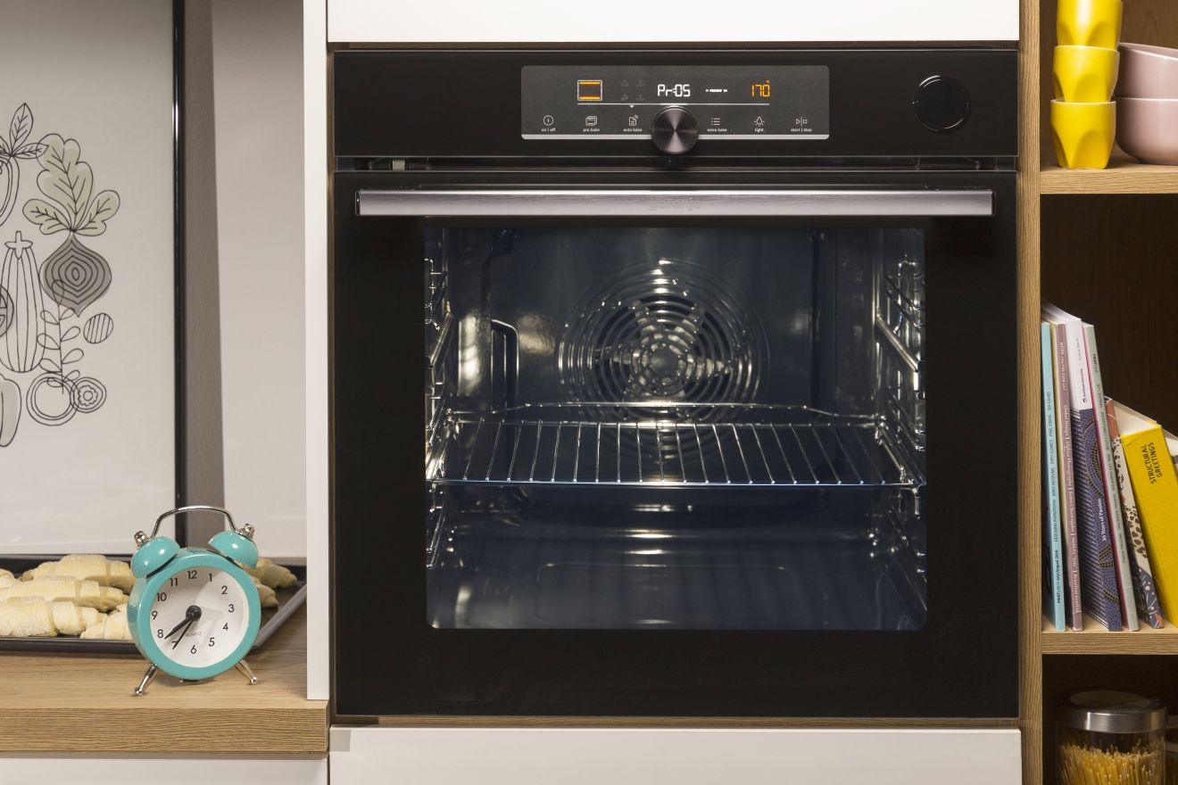 Sütő digitális kijelzővel. Belsejében rácsok és ventilátor található. Az ajtó nyitva.