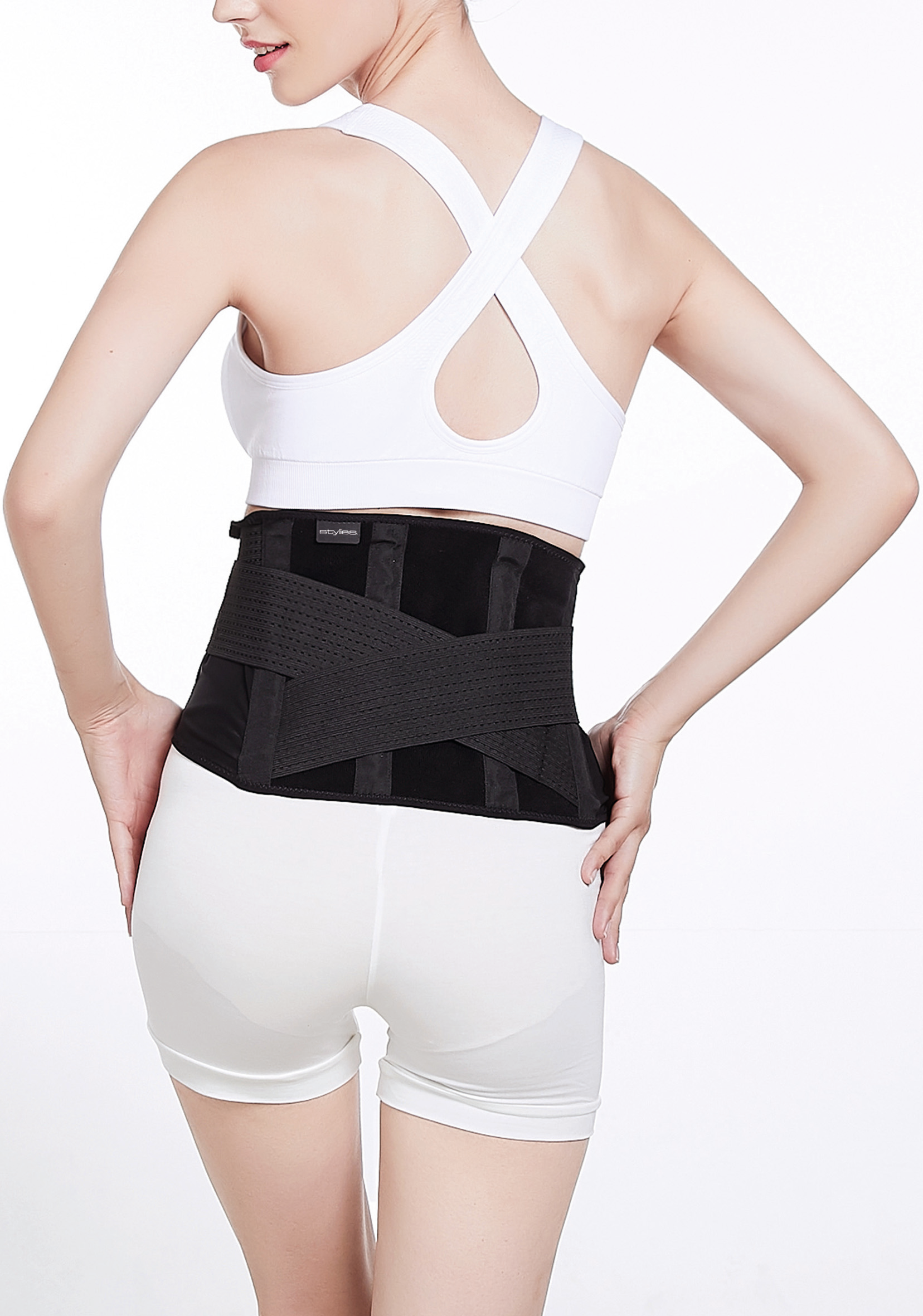 Donna con top e pantaloncini bianchi, indossa anche una cintura di supporto lombare nera.