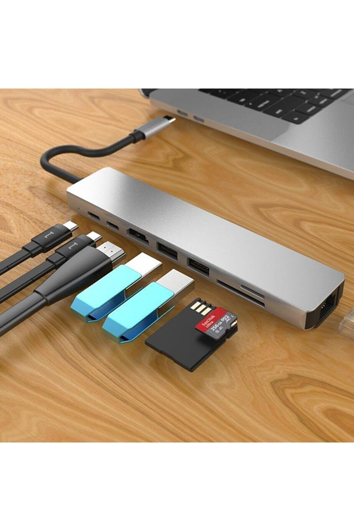 Ahşap bir masa üzerinde çeşitli bağlantı noktaları, kablolar ve USB sürücülerine sahip gümüş renkli bir USB hub.
