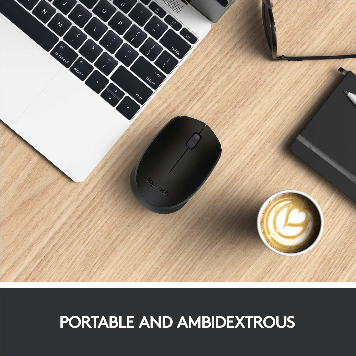 Un ordinateur portable, une souris Logitech noire, un café avec un cœur et un carnet sur une table en bois.