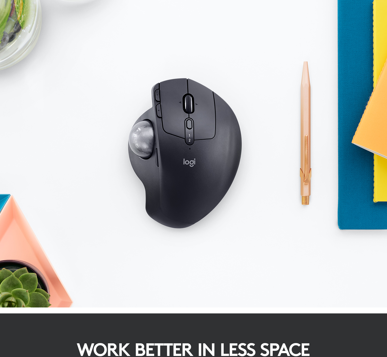 Souris Logitech noire avec trackball sur une surface blanche avec fournitures de bureau.