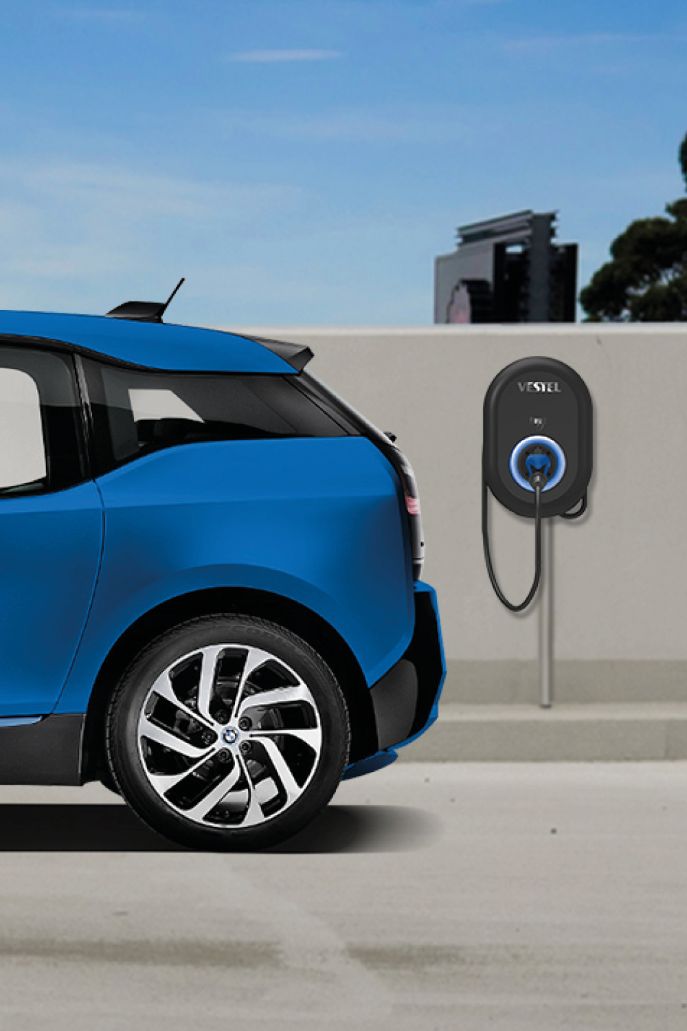 Blaues Elektroauto neben einer Ladestation an einer Wand vor klarem Himmel.