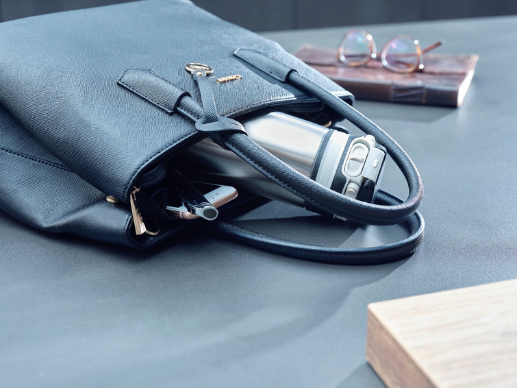 Hand in handbag with water bottle and glasses.