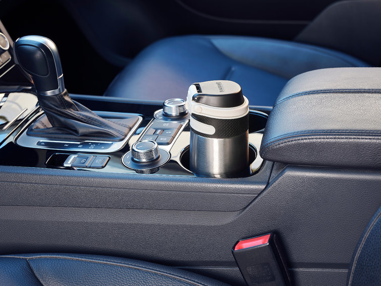 Car interior with a cup in a holder. Black steering wheel and console.
