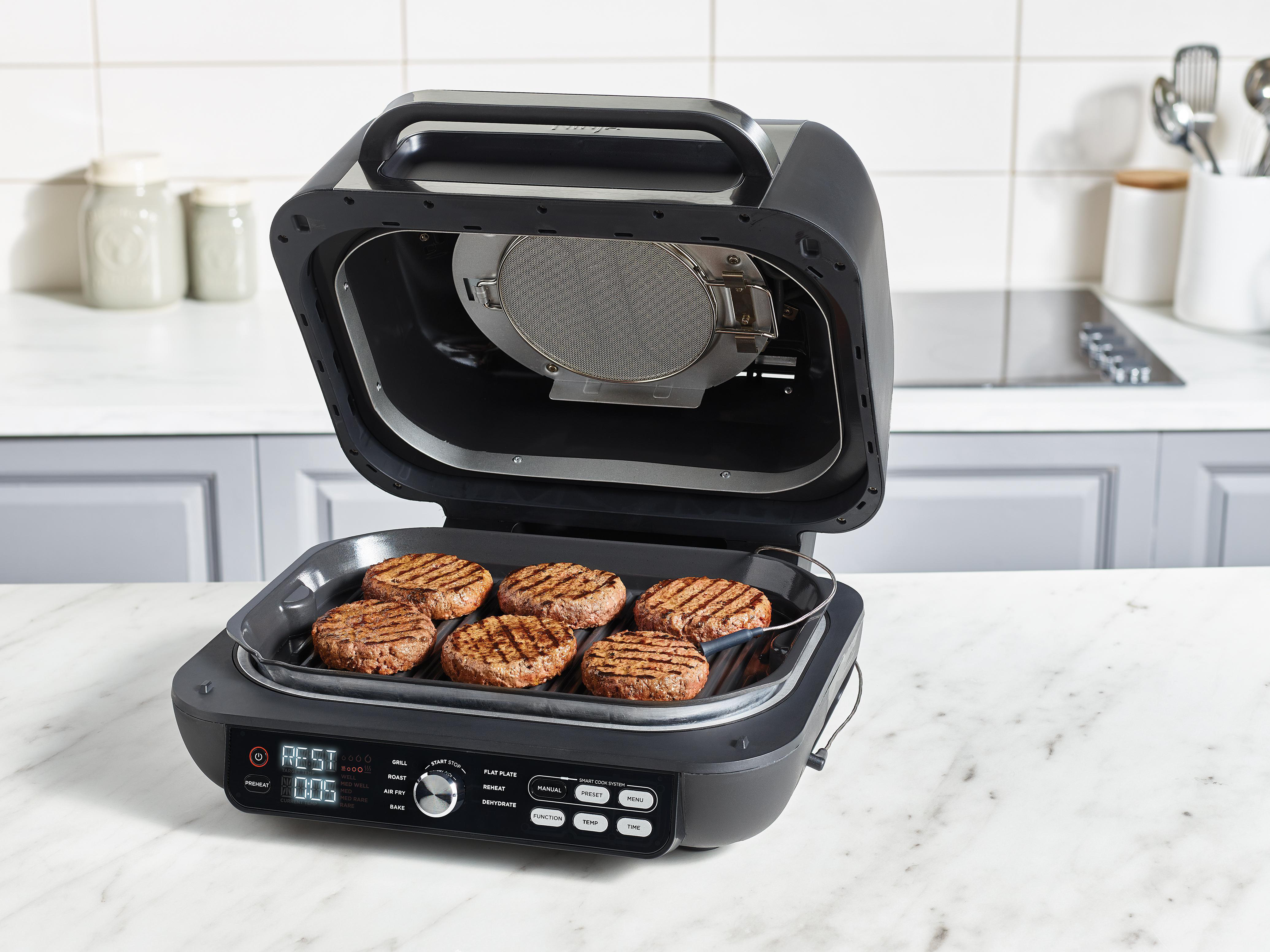 Ein offener Grill mit sechs gebratenen Burgern, die auf dem Rost liegen.