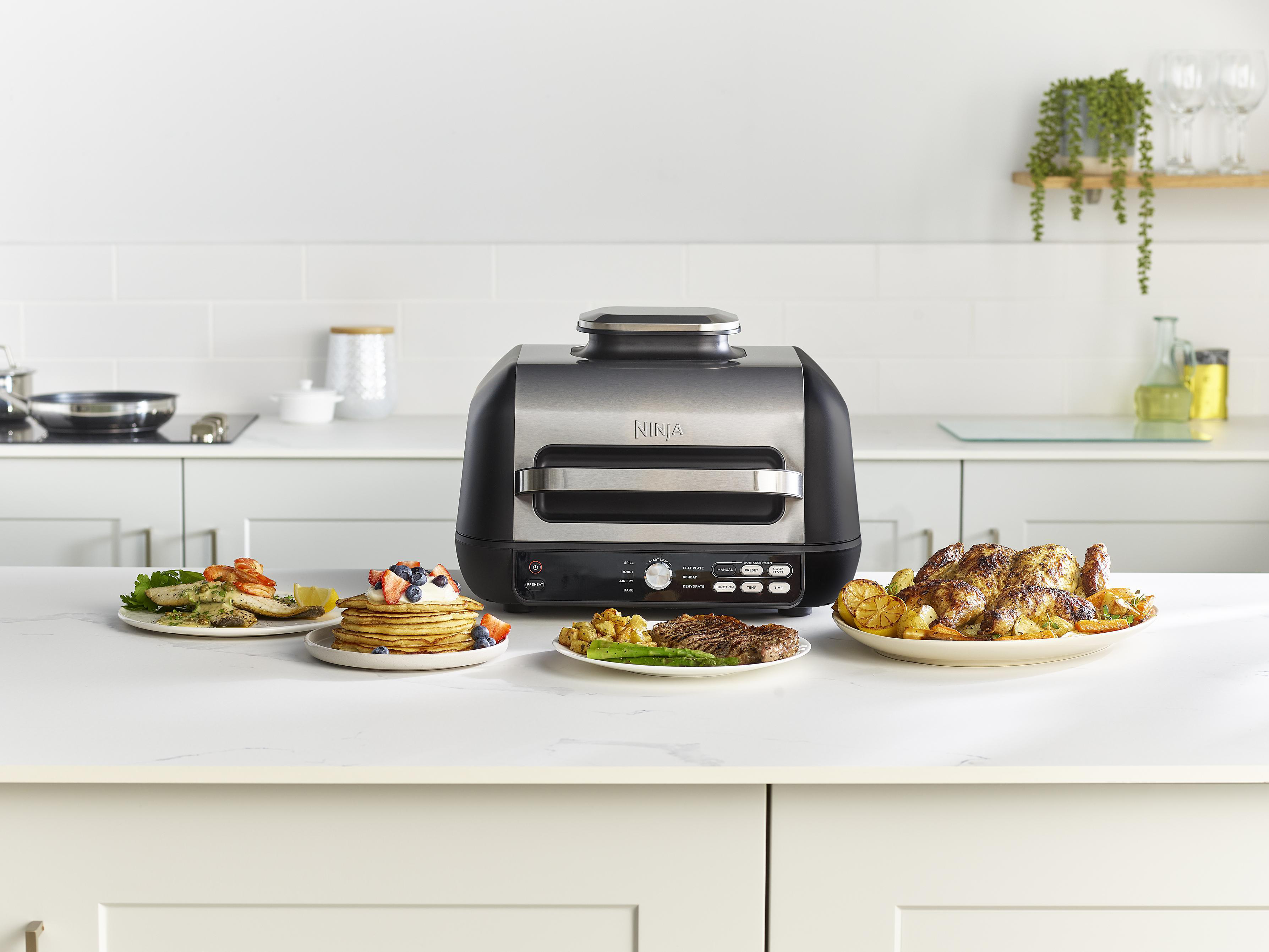 Ein Ninja Grill mit drei Tellern mit Essen: Fisch, Pfannkuchen und Brathähnchen.