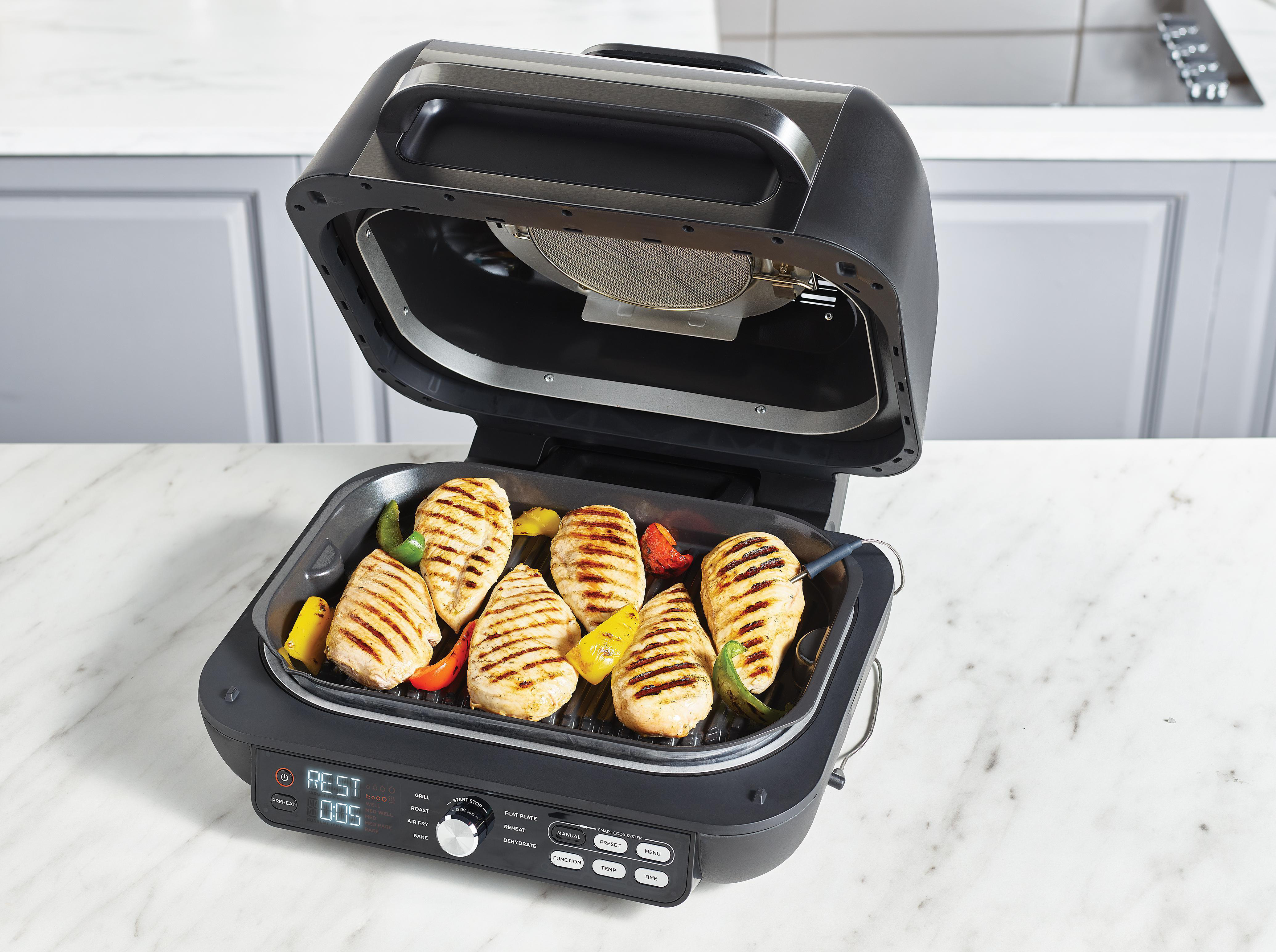 Gegrilltes Hähnchen und Gemüse in einem offenen Elektrogrill mit digitaler Anzeige.