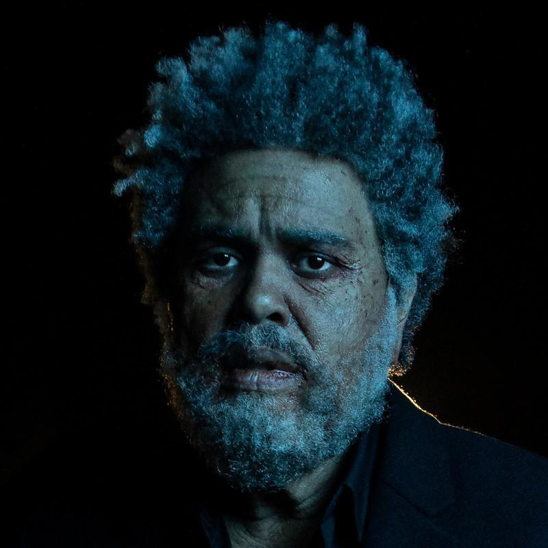 Nahaufnahme-Porträt von The Weeknd mit grauen Haaren, Bart und nachdenklichem Ausdruck.