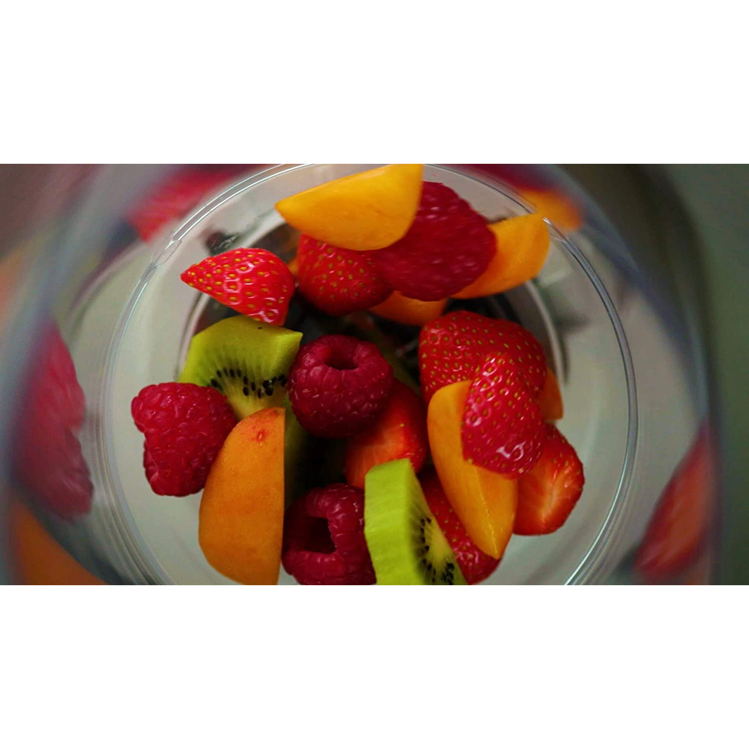 Un cuenco transparente lleno de fruta colorida, incluyendo fresas, kiwi y rodajas de naranja.