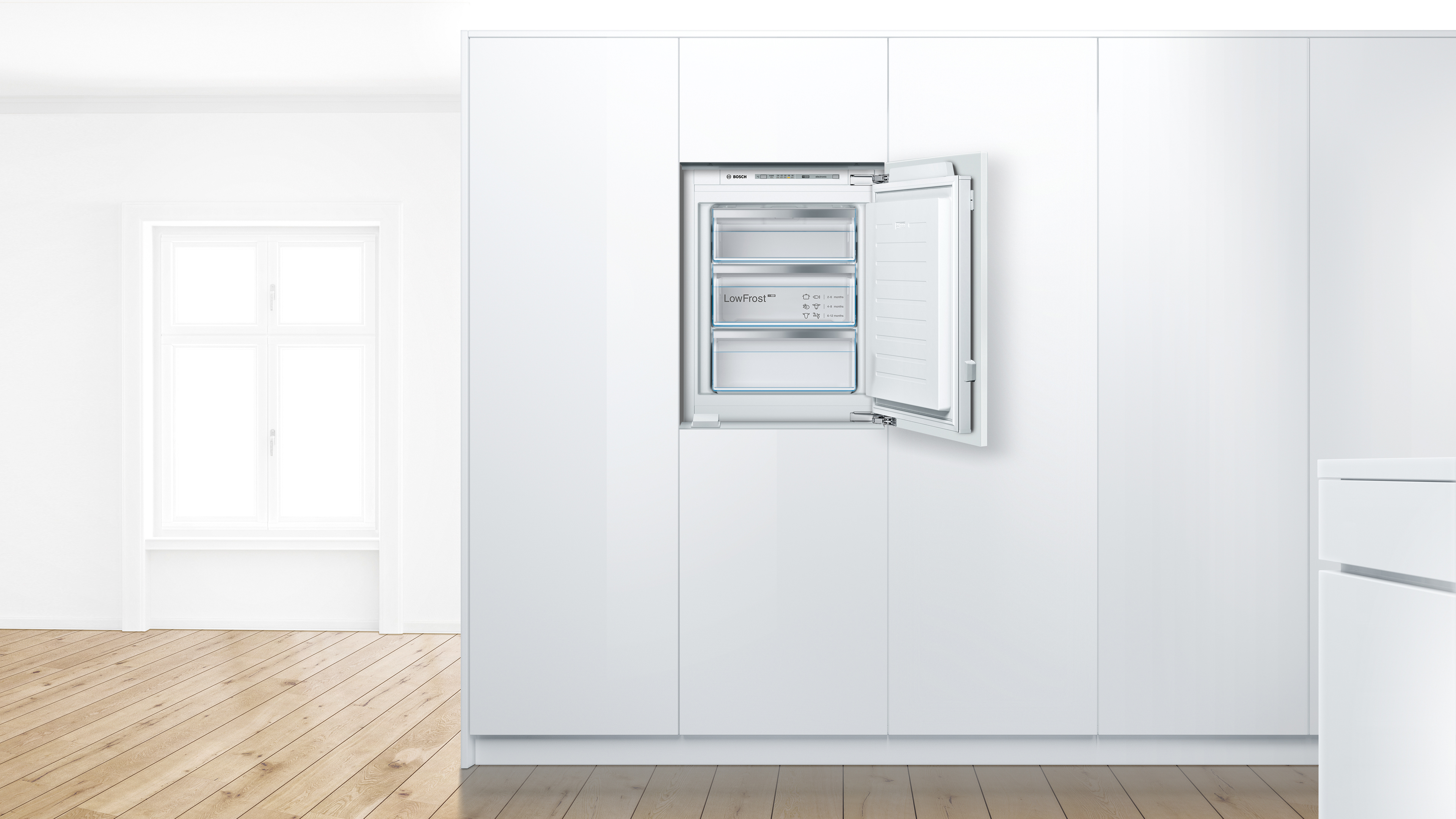 Ein eingebauter weißer Kühlschrank mit geöffneter Tür, der die Inneneinrichtung zeigt, vor einem weißen Küchenschrank.