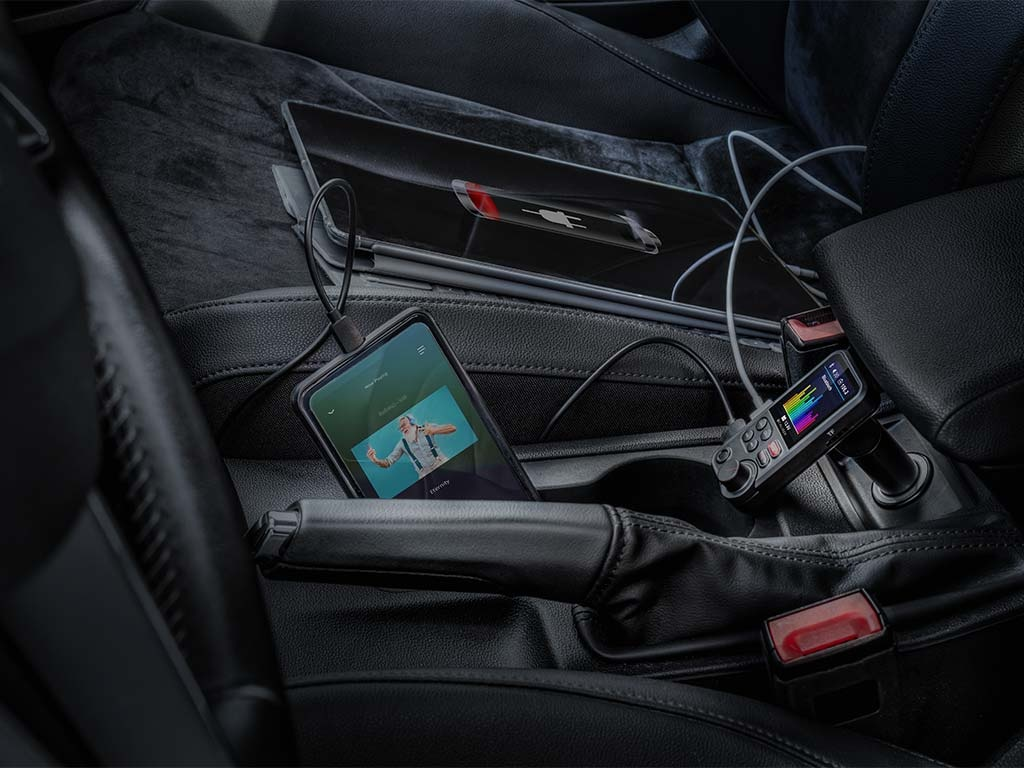 A car's interior with a phone and a control device in the center console.