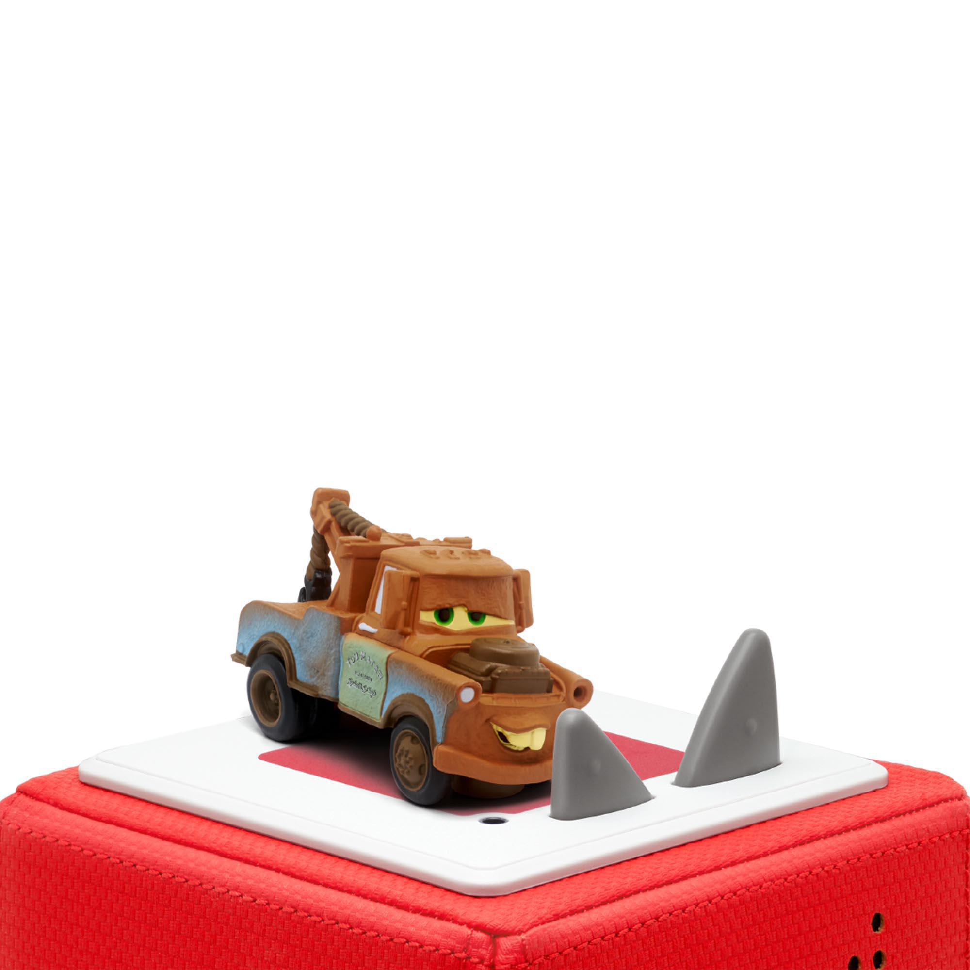 Spielzeugauto Mater aus Cars mit Haifischflossen auf roter und weißer Fläche.