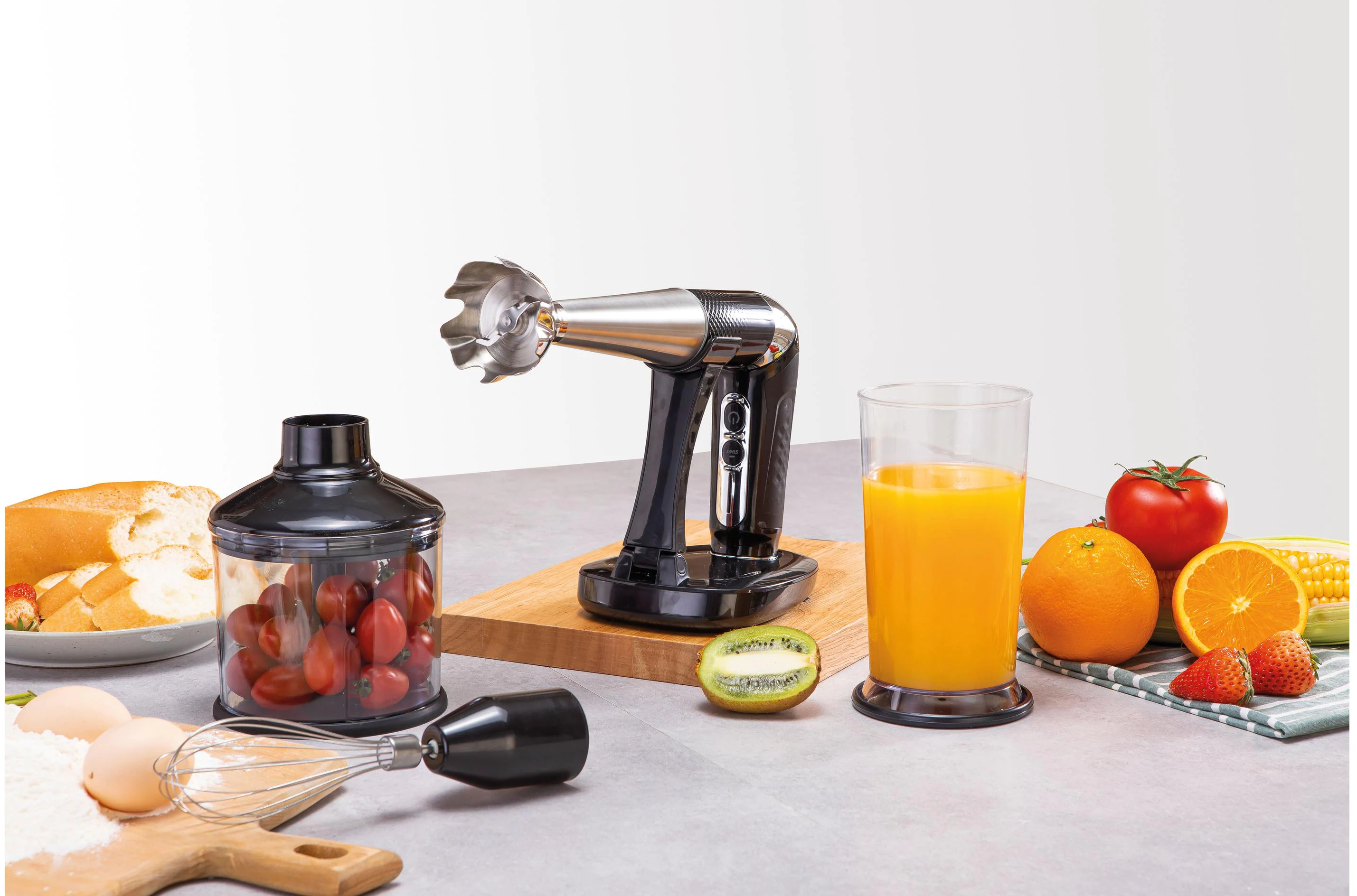 Un frullatore a immersione con accessori e alcuni ingredienti alimentari.