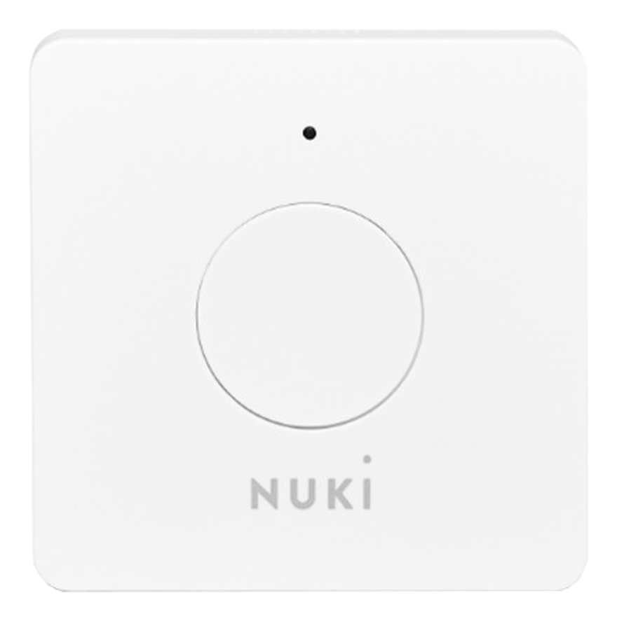 Ein weißes Smart-Home-Gerät in quadratischer Form mit einem kreisförmigen Knopf und einem schwarzen Punkt.