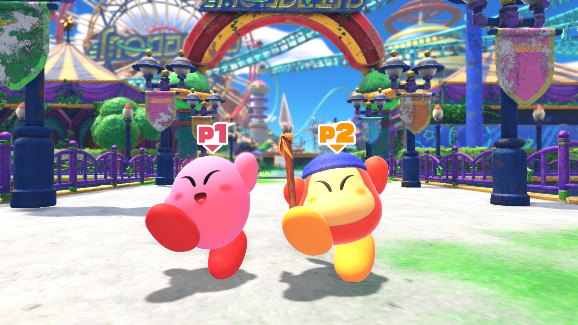 Due personaggi di Kirby, rosa e arancione, corrono verso lo spettatore in un'ambientazione da carnevale.