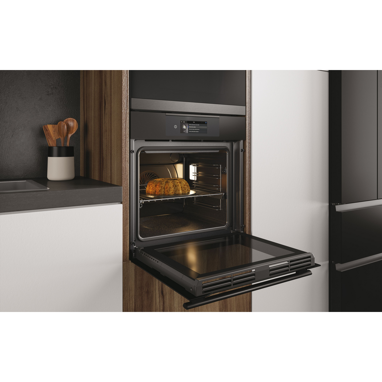 Un horno empotrado con la puerta abierta, una hogaza de pan dentro. Madera y paneles negros alrededor.