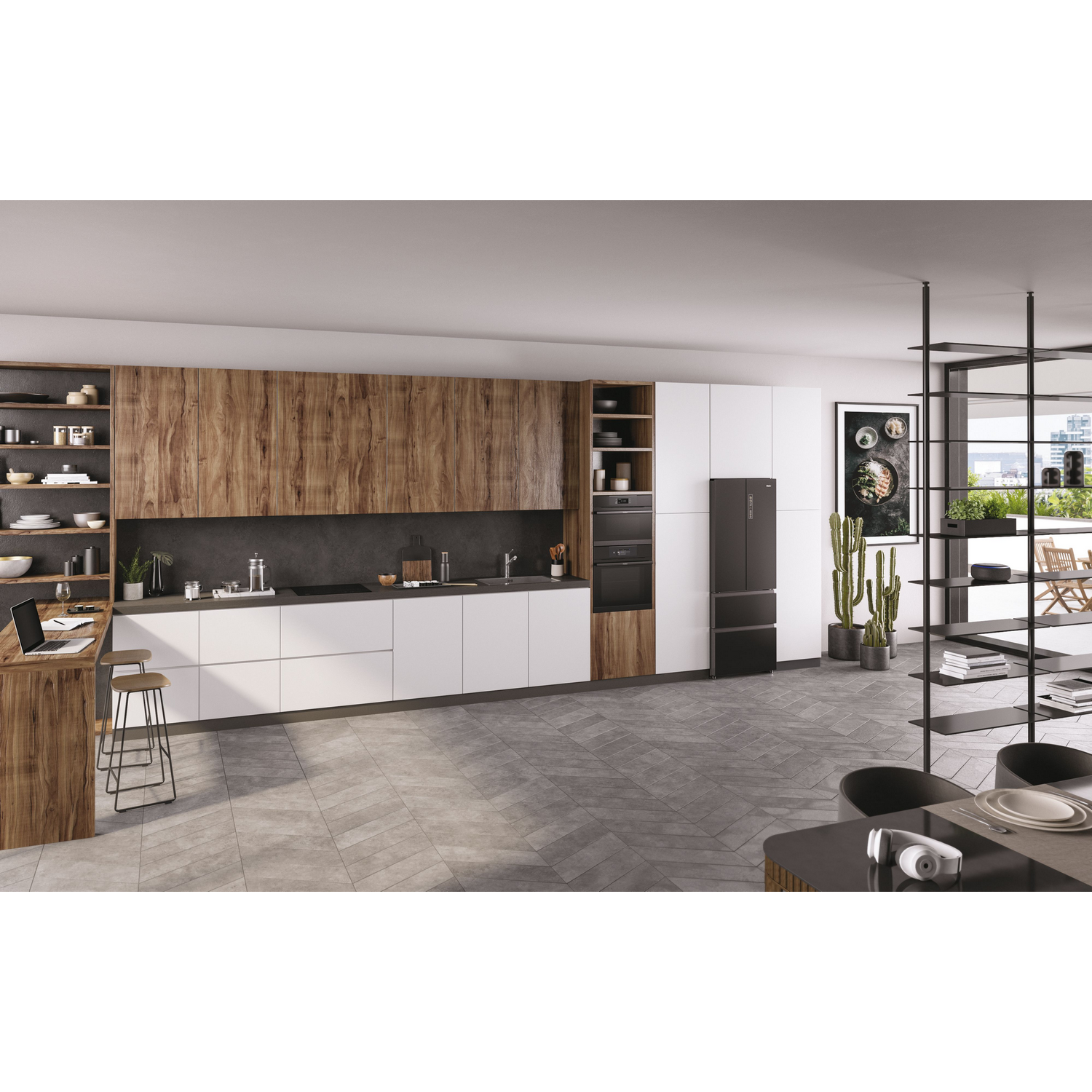 Cocina moderna con gabinetes de madera y blancos, isla con laptop, refrigerador negro y piso gris. Incluye plantas.