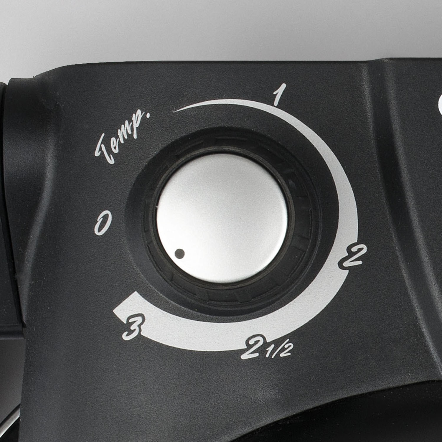 Primo piano di un quadrante di controllo nero con numeri e testo. Sfondo grigio.