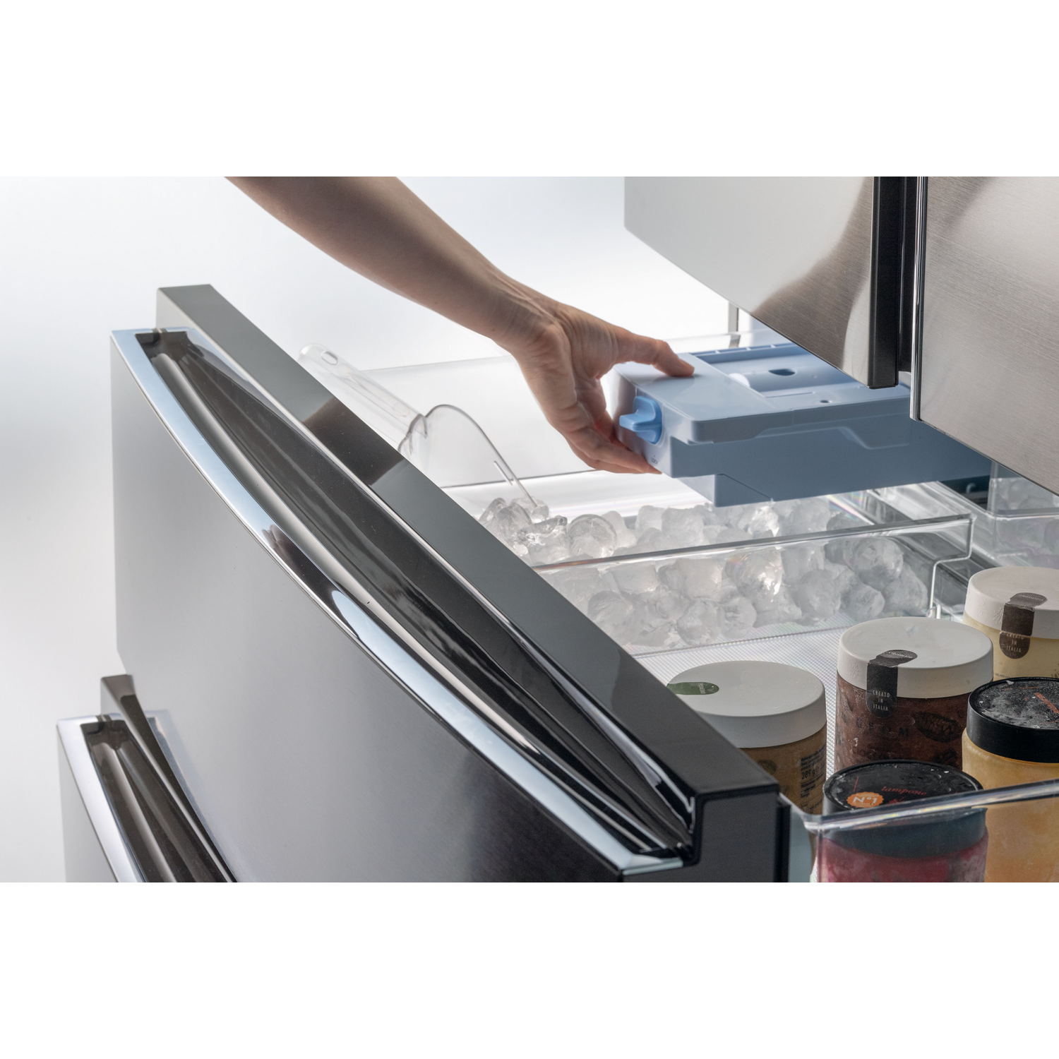 Una mano se mete en un cajón del refrigerador para sacar una cubitera.