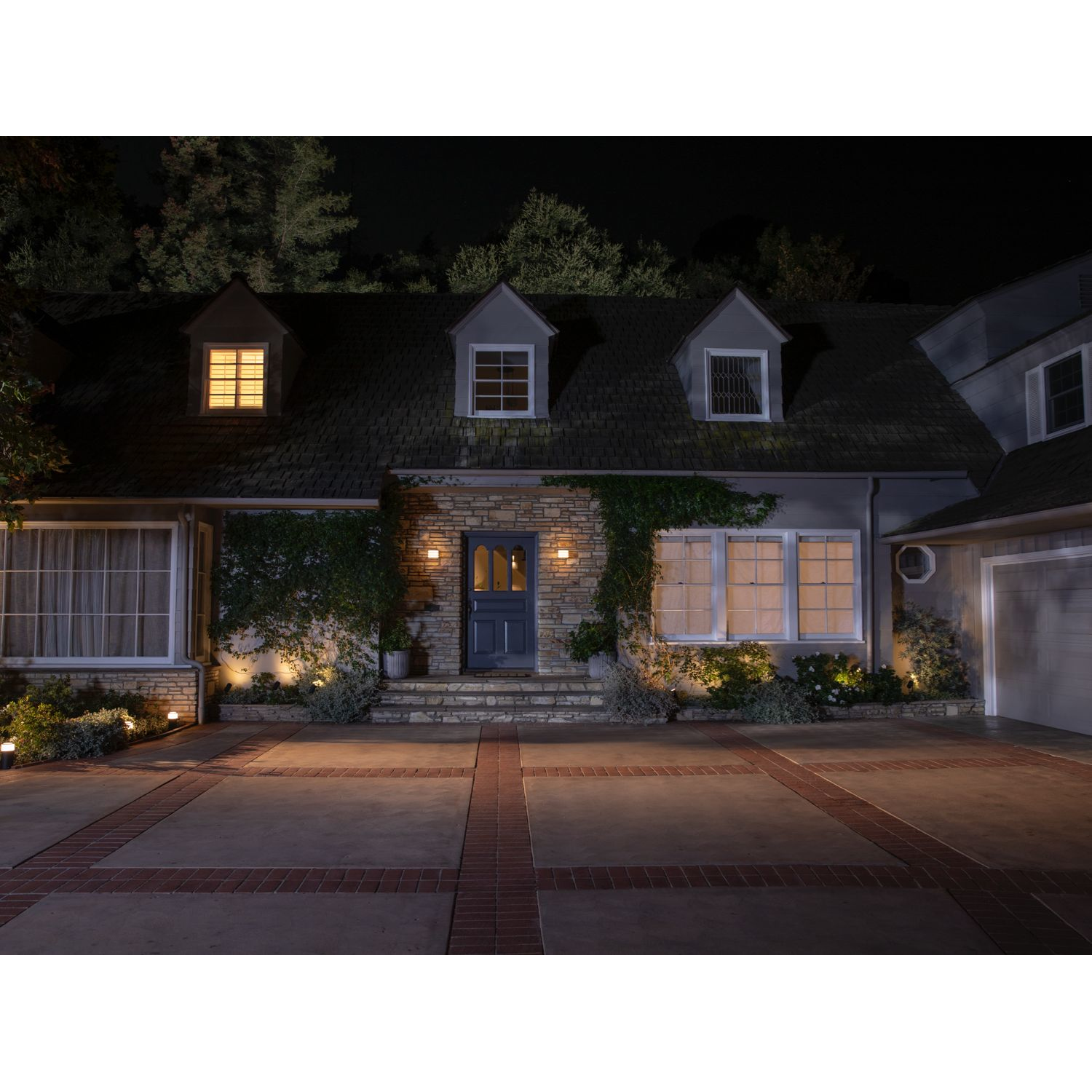 Escena nocturna, casa con luces encendidas; entrada.