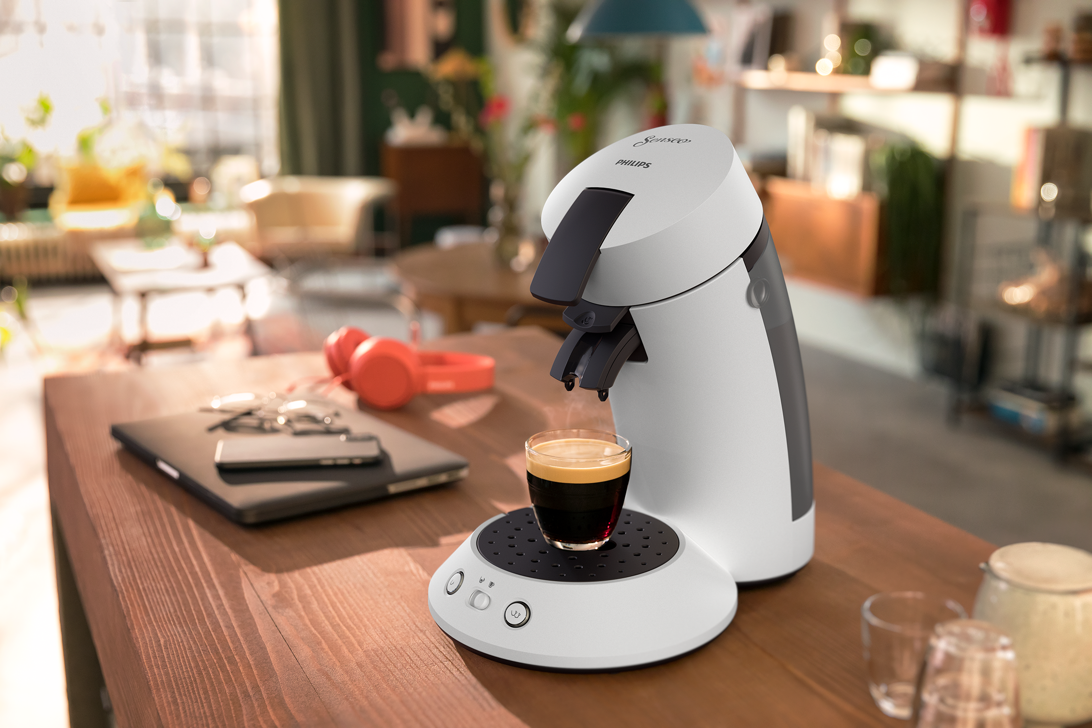 Coffee machine making espresso. Cup with coffee under the spout. Wooden table in the scene.