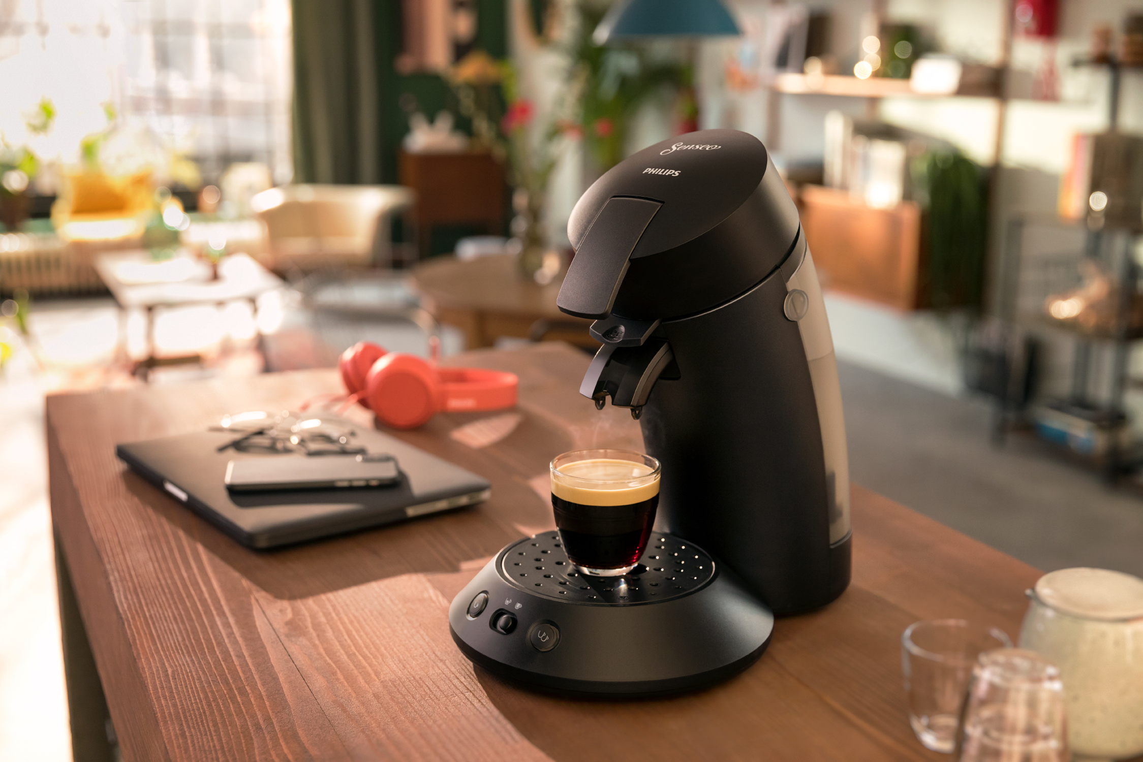 Black coffee machine with a cup of coffee on the wooden table.