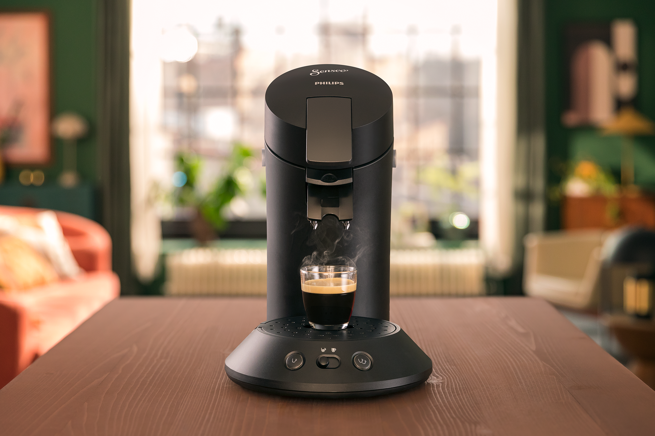 A black Philips Senseo coffee machine with a cup and steam coming from it.