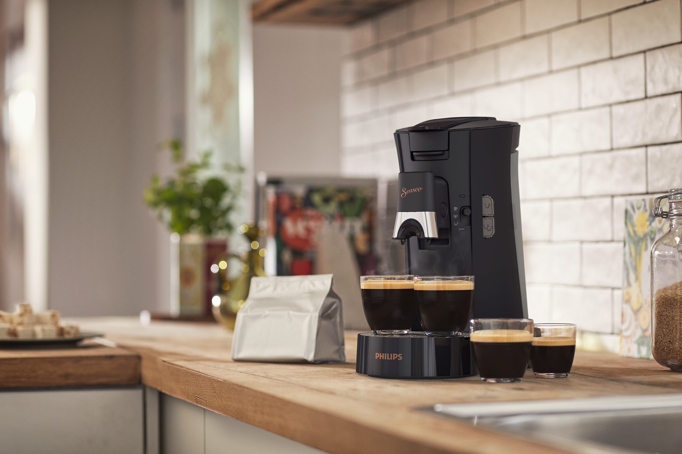 Zwarte Philips Senseo koffiemachine met kopjes en koffiebonen op een houten aanrecht.