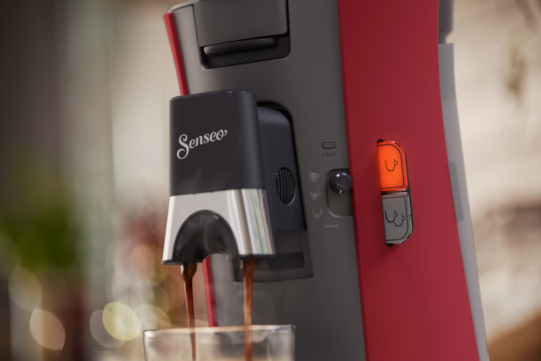 Close-up of a red and black Senseo coffee machine, pouring coffee into a glass.
