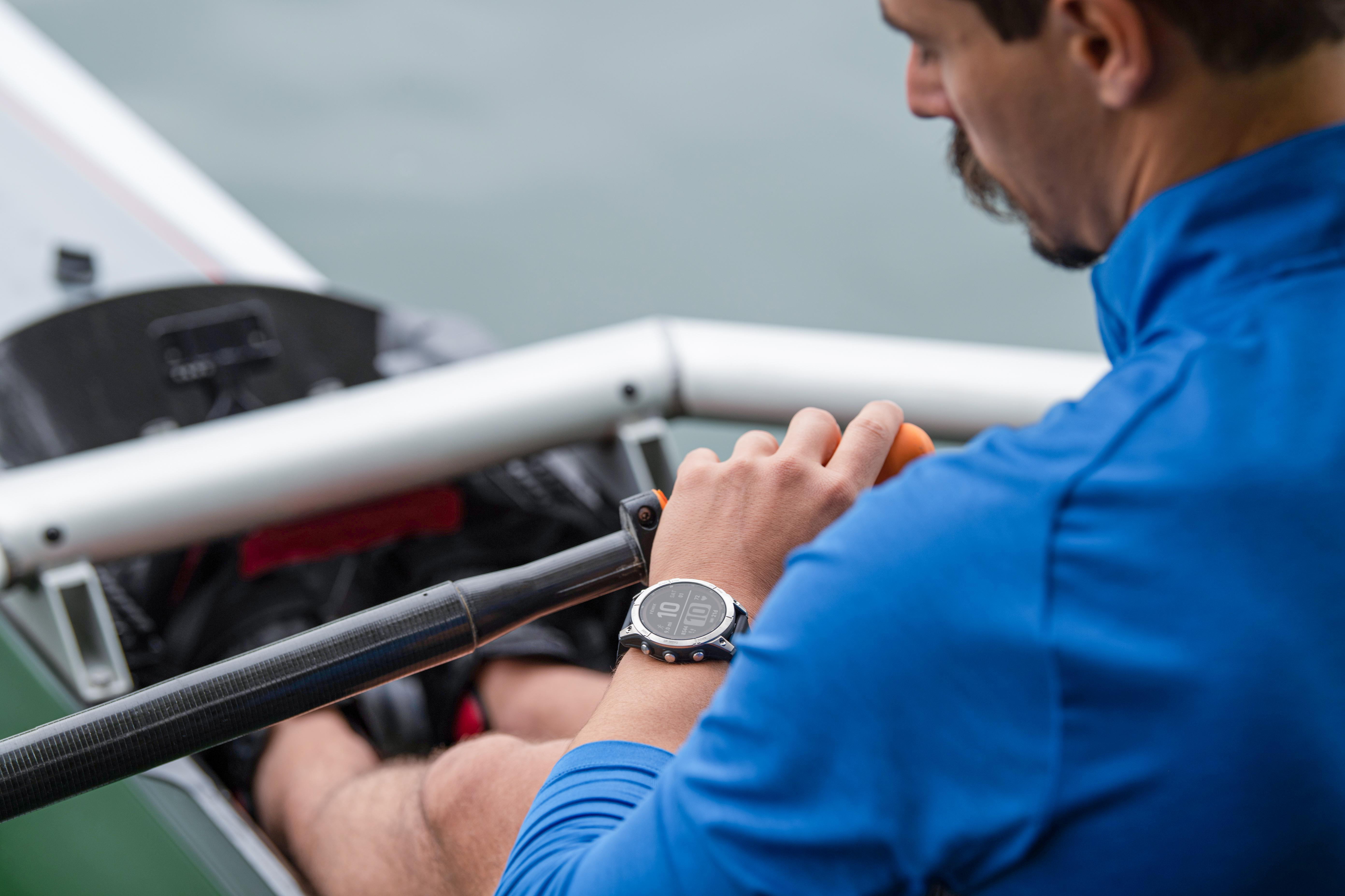 Ein Mann mit Smartwatch, der ein Ruder hält, mit Wasser im Hintergrund.