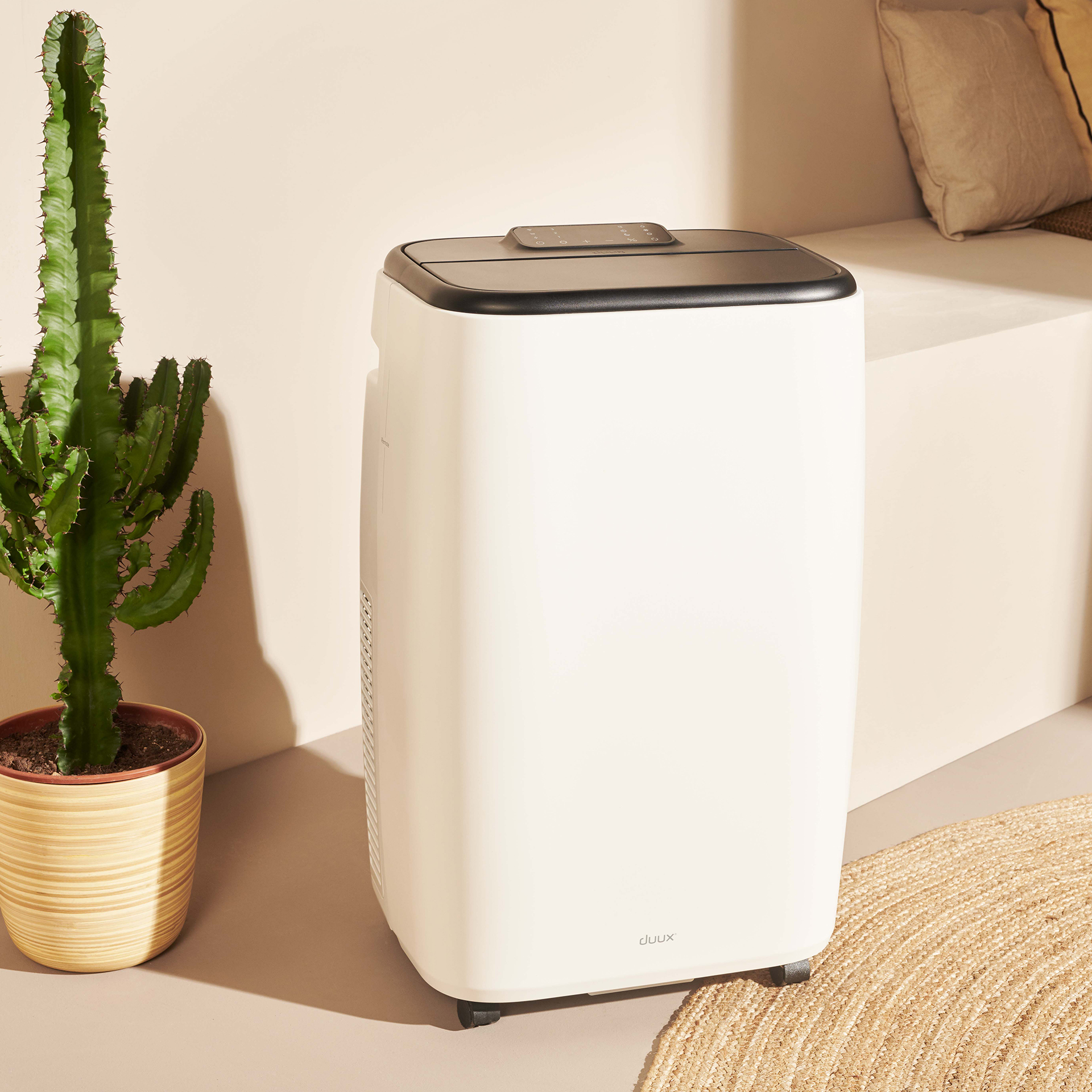 Un climatiseur blanc avec un dessus noir est à côté d'un cactus. La scène est éclairée d'une lumière chaude.