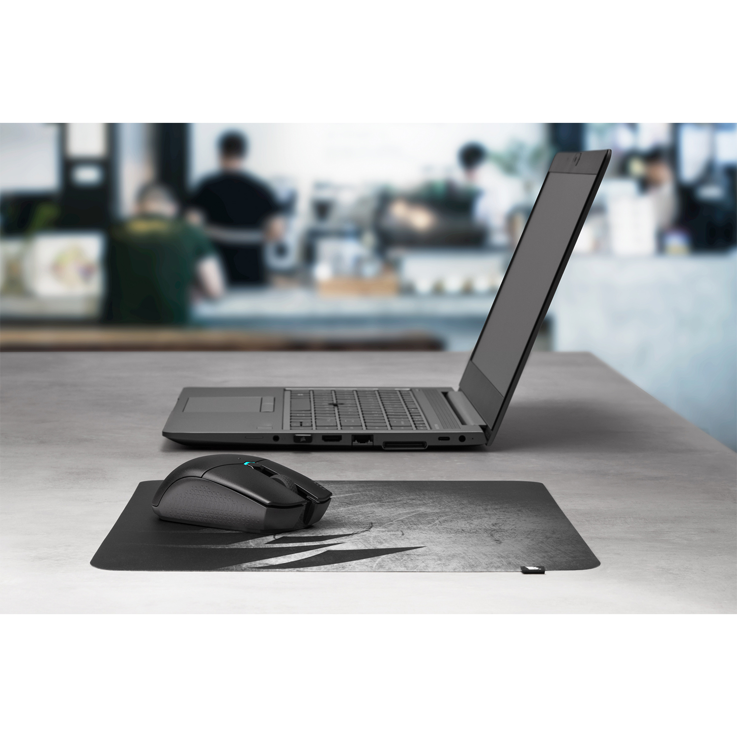 Laptop, mouse e tappetino su un tavolo; sfondo sfocato.