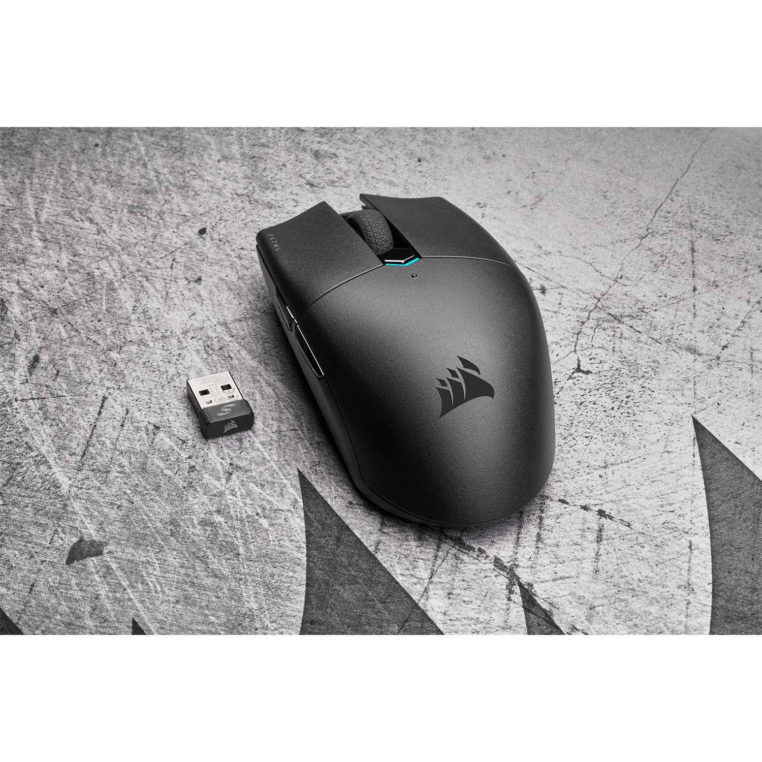 Mouse wireless nero con ricevitore USB, su superficie grigia strutturata.