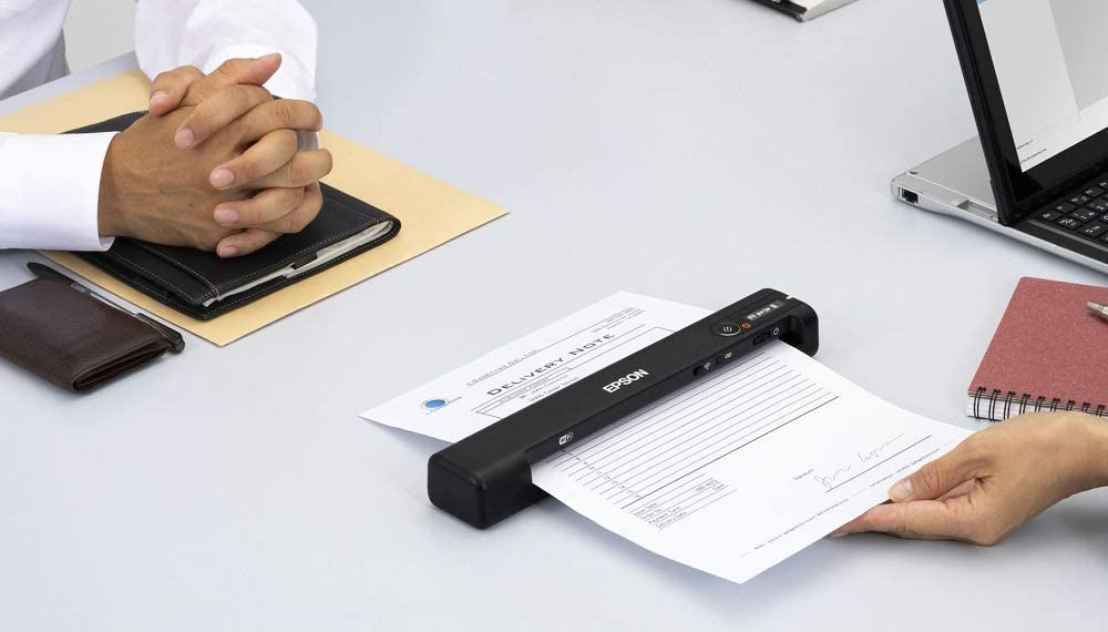 Persoon scant een document. Scanner op tafel, handen zichtbaar.