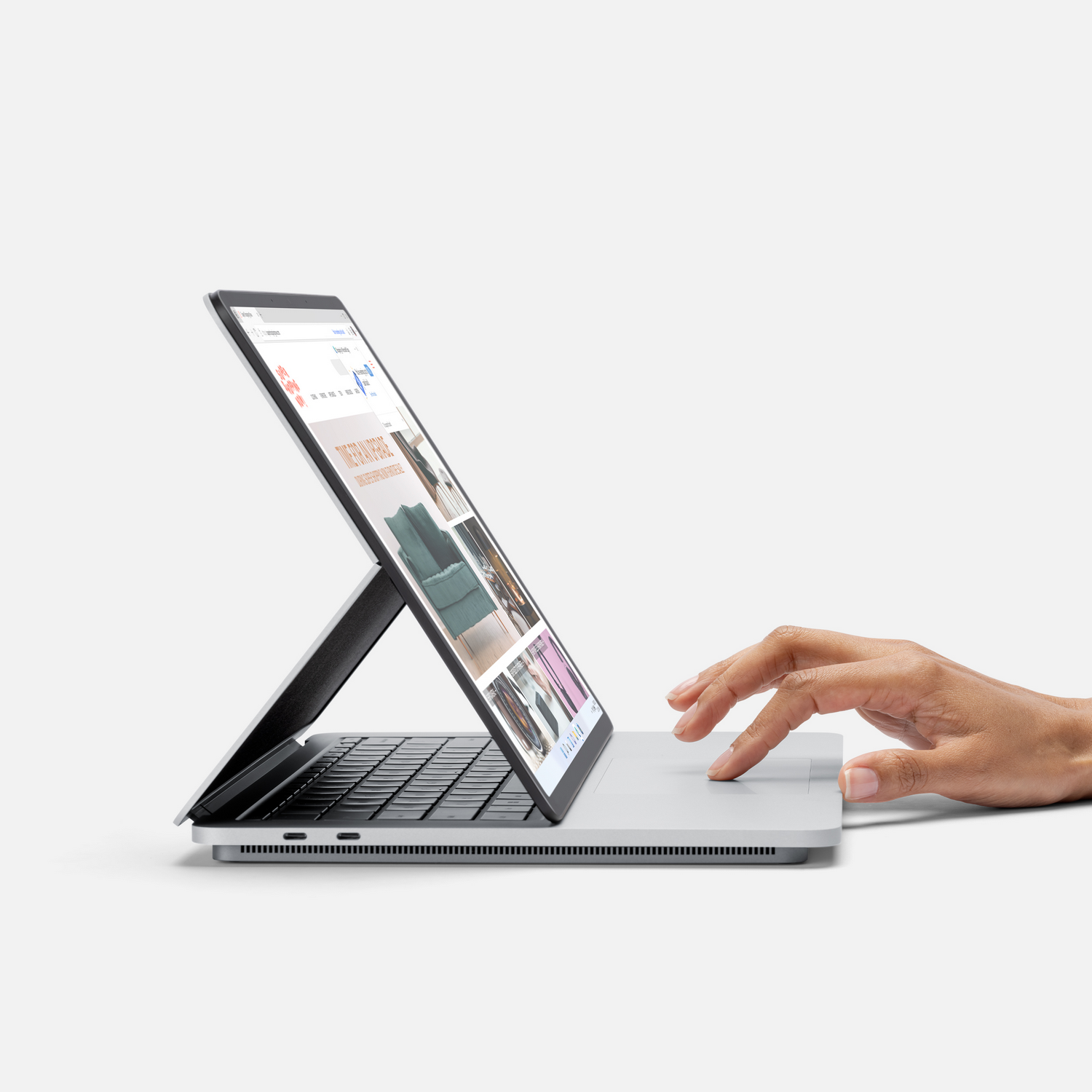 Mano de una persona usando una laptop con la pantalla inclinada hacia arriba, mostrando un sitio web.