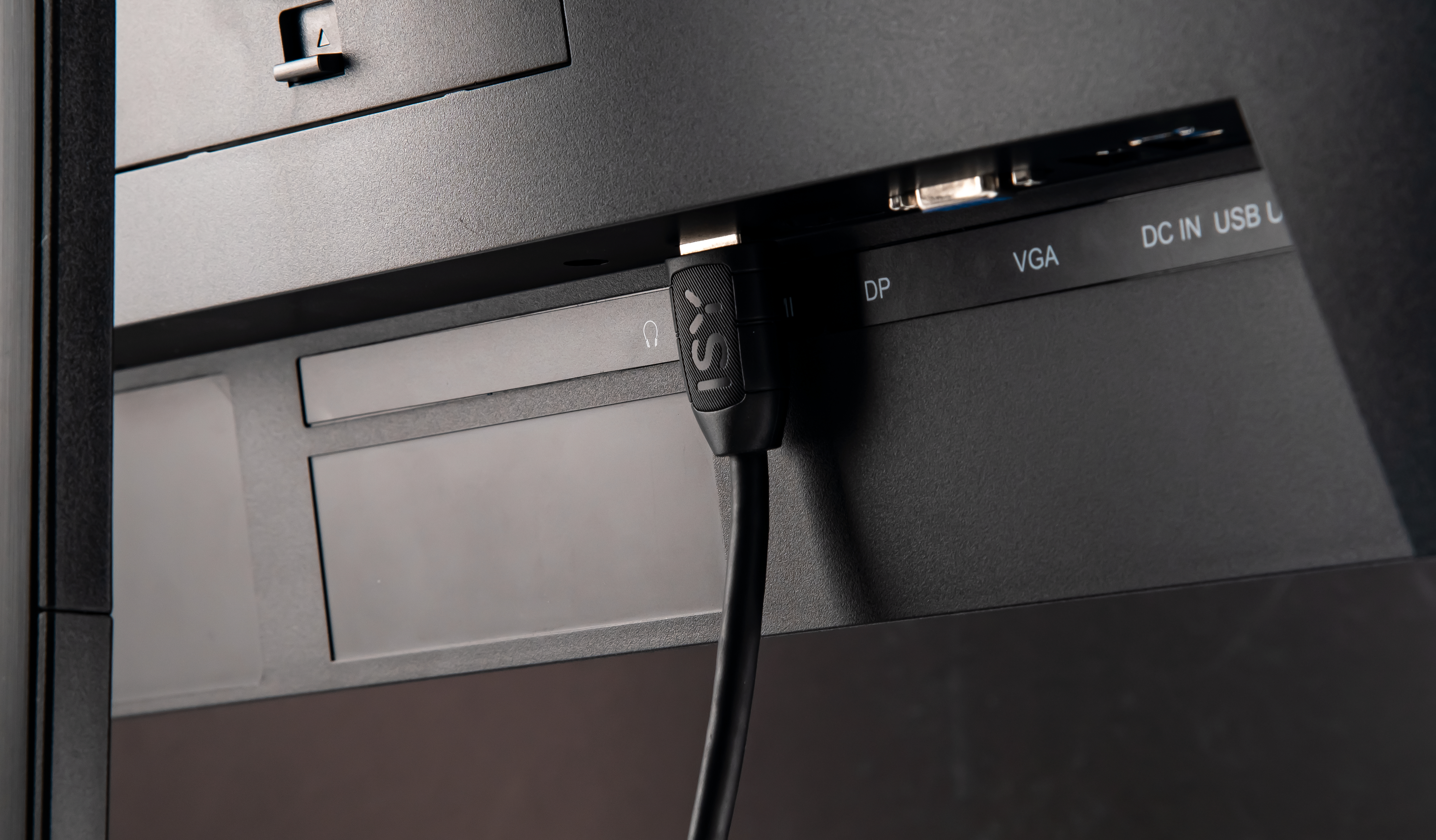 Nahaufnahme der Rückseite eines Monitors. HDMI-Kabel eingesteckt mit DP-, VGA- und USB-Anschlüssen sichtbar.