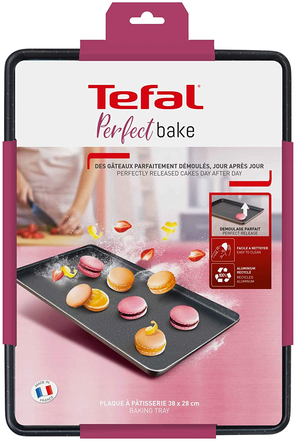 Egy sütőlemez macaronokkal. A tálca egy rózsaszín csomagban van.