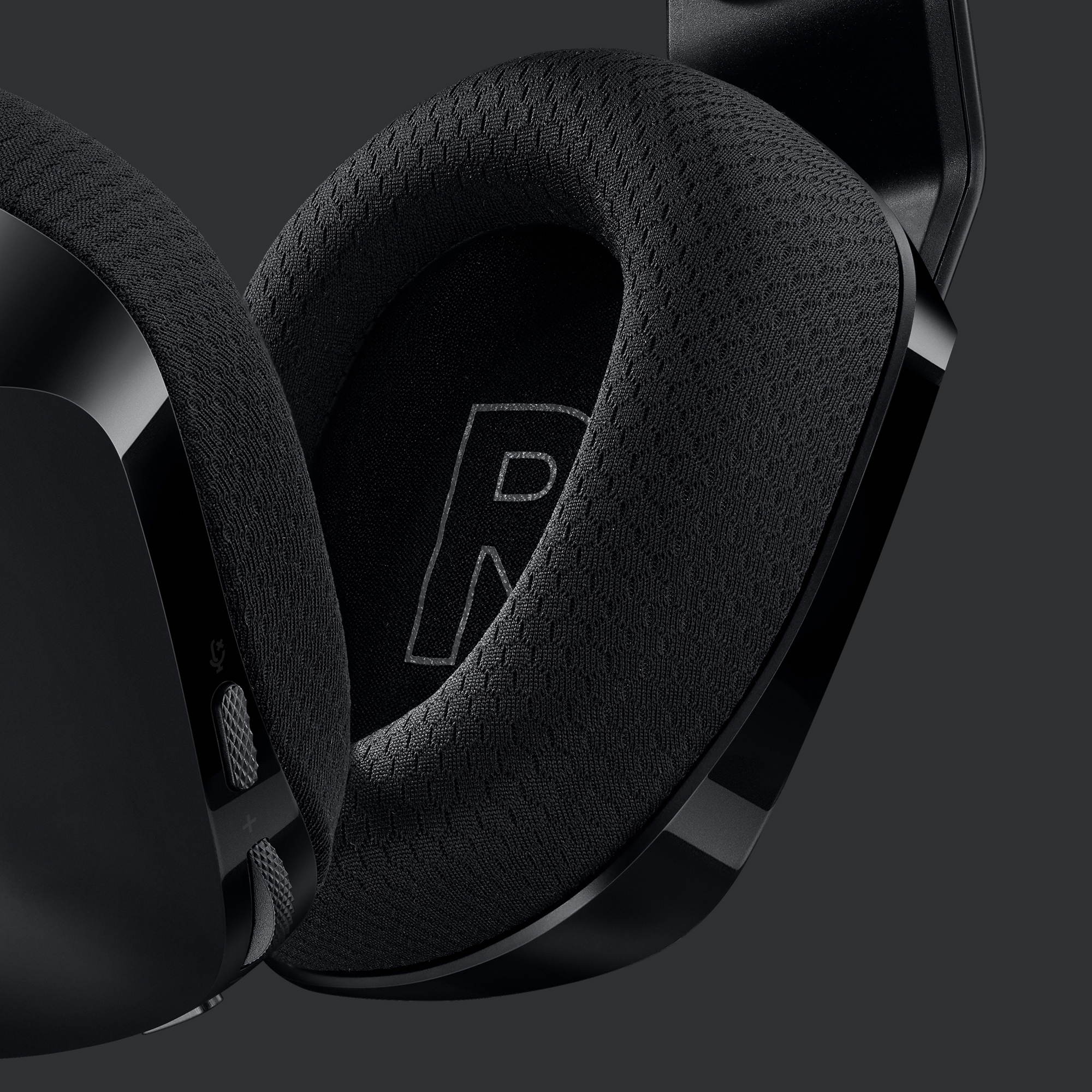 Black gaming headset ear cushion. The letter 'R' is visible on the fabric.
