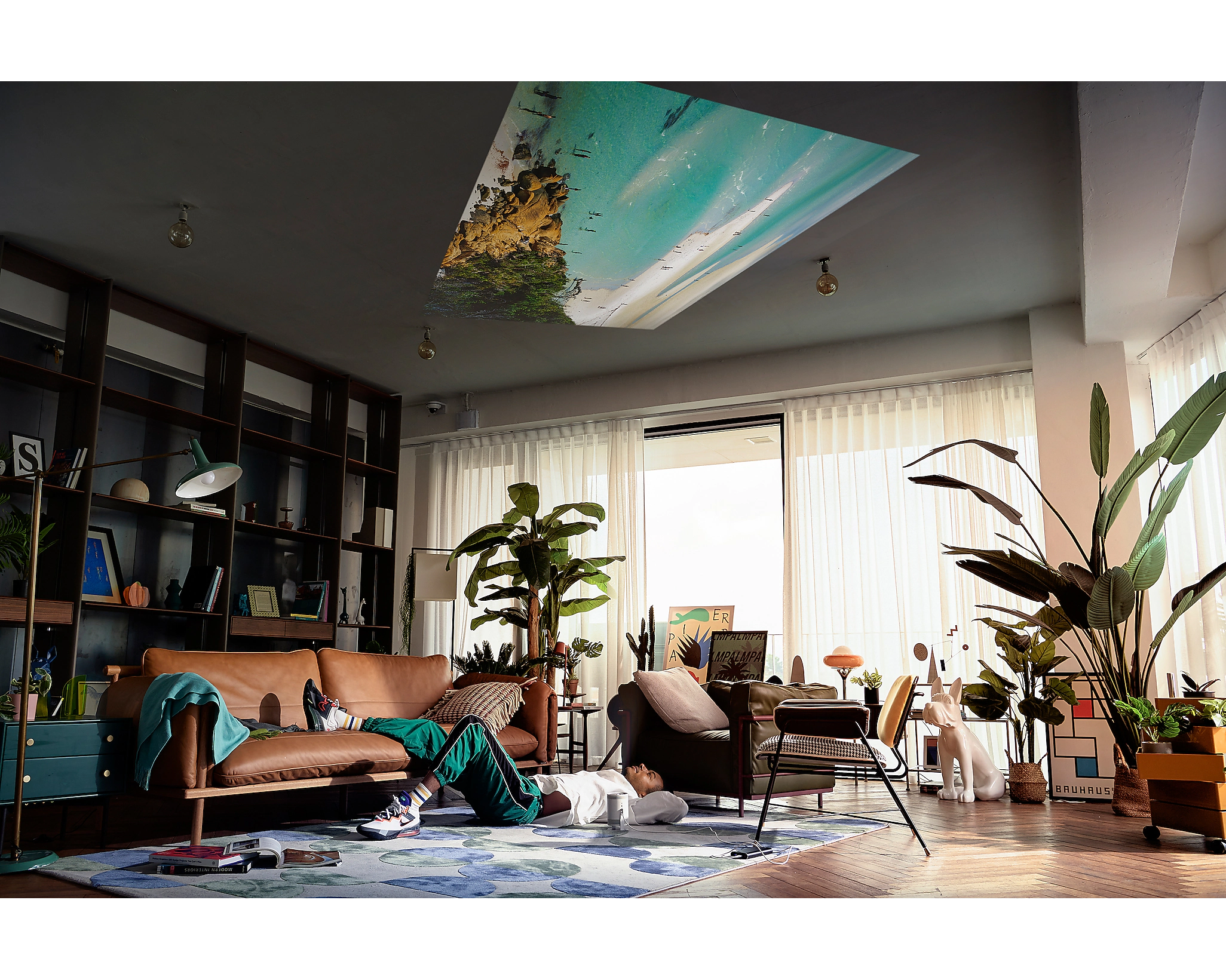 Person am Boden, projiziertes Bild an der Decke, modernes Wohnzimmer.