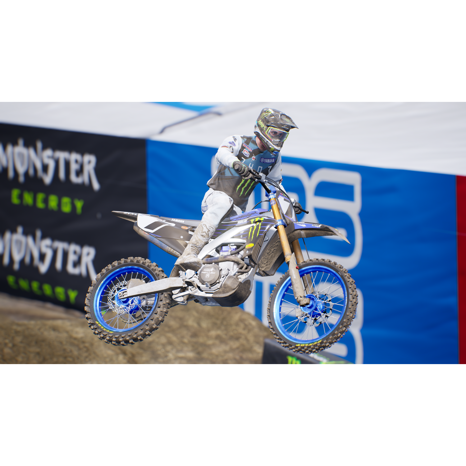 Un piloto de motocross en una moto Yamaha en el aire, sobre una pista. Combinación de colores azul y blanco.