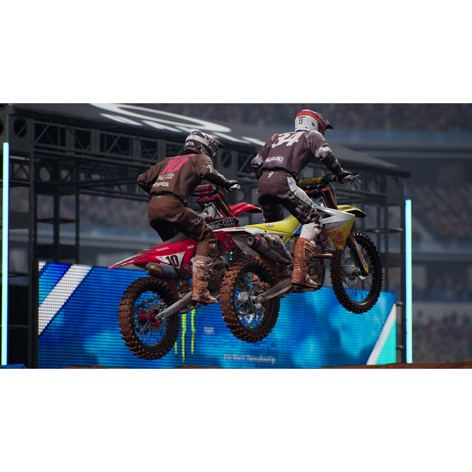Dos pilotos de motocross en el aire. Están en motos de cross en un estadio.
