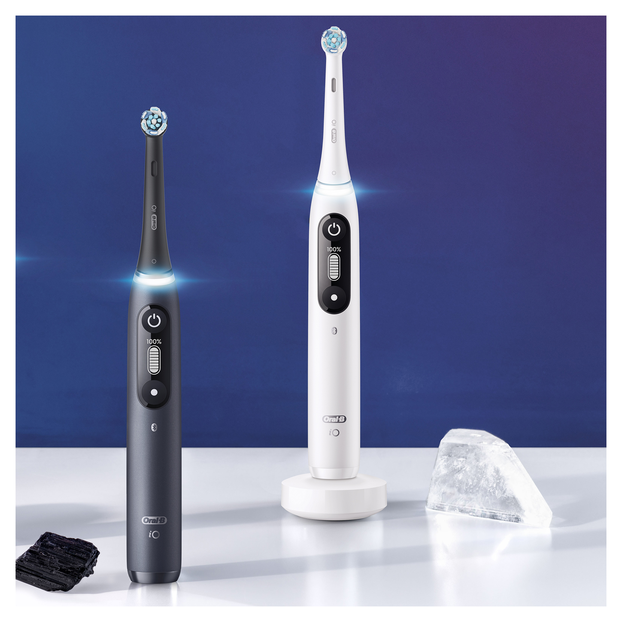 Két fekete-fehér Oral-B elektromos fogkefe kék felületen.